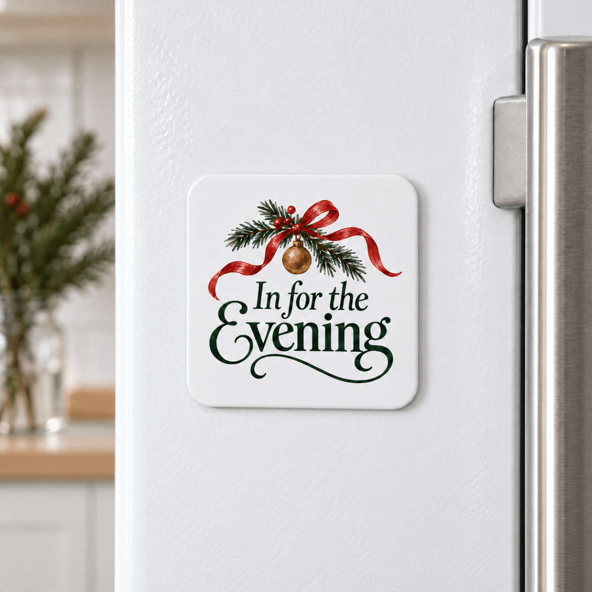 Square In for the Evening Christmas Magnet on a white refrigerator, featuring a pine branch with an evergreen ribbon and a painted ornament above the words “In for the Evening.”
