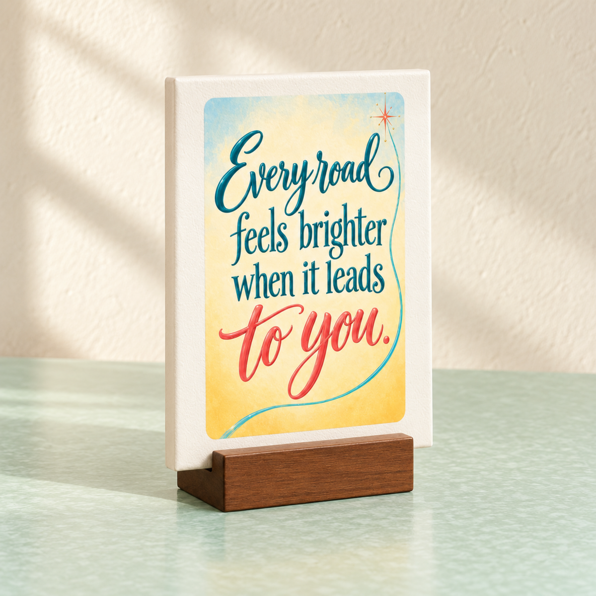 Every Road Feels Brighter Mini Sign | Chrome & Starlight: a small rectangular mini canvas sign in a wooden stand reading, “Every road feels brighter when it leads to you.”.