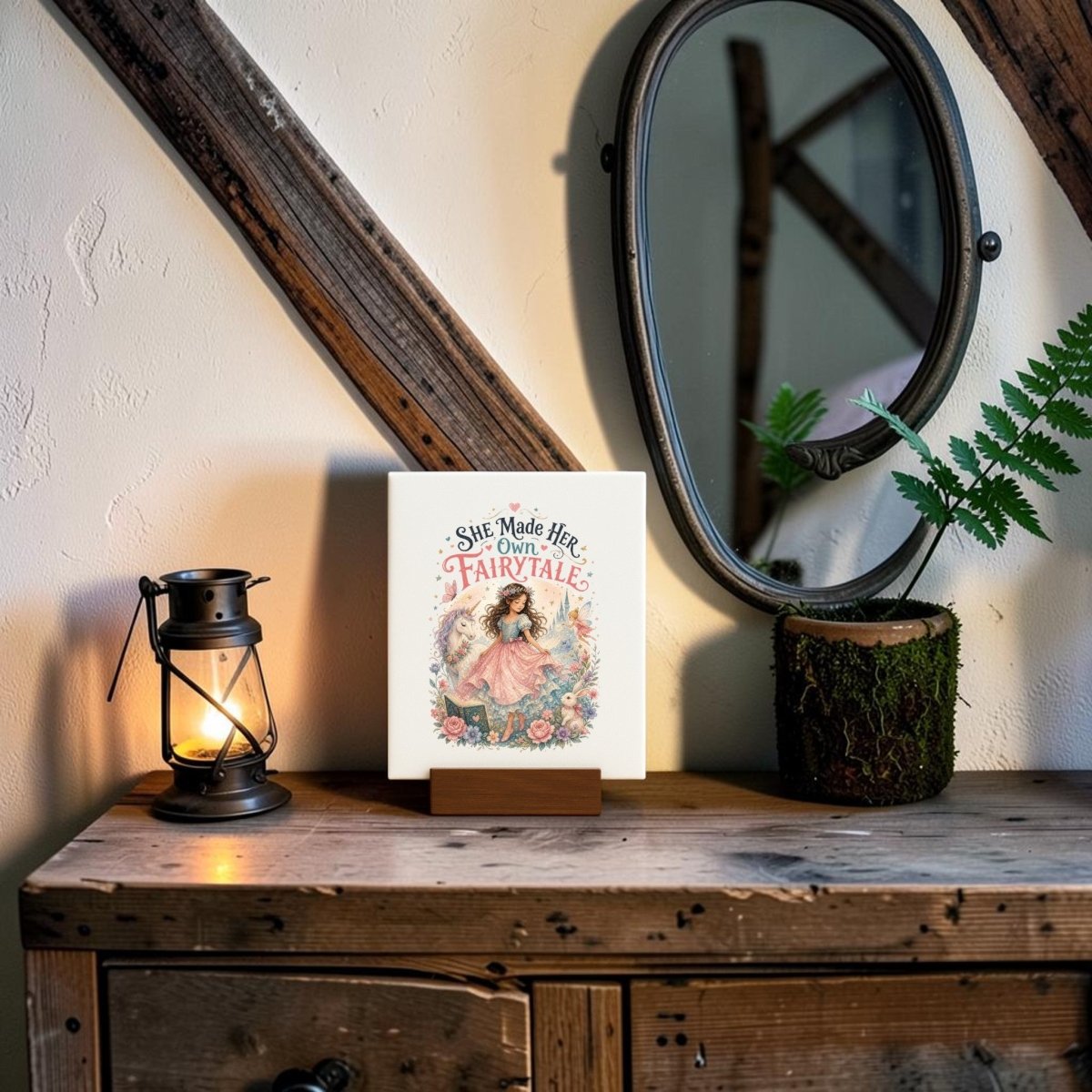 A rustic dresser displays the Mirabilia Boutique "She Made Her Own Fairytale" Mini Canvas alongside a lantern, a mirror, and a fern in a moss pot. Wood paneling lines the wall, and warm lighting creates a cozy, inviting atmosphere—perfect for children’s room decor.