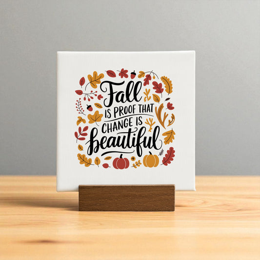 The Fall Is Proof Mini Sign by Mirabilia Boutique features “Fall is proof that change is beautiful” on a wooden stand, surrounded by leaves, an acorn, branches, and pumpkins—an inspirational autumn decor accent for your home.