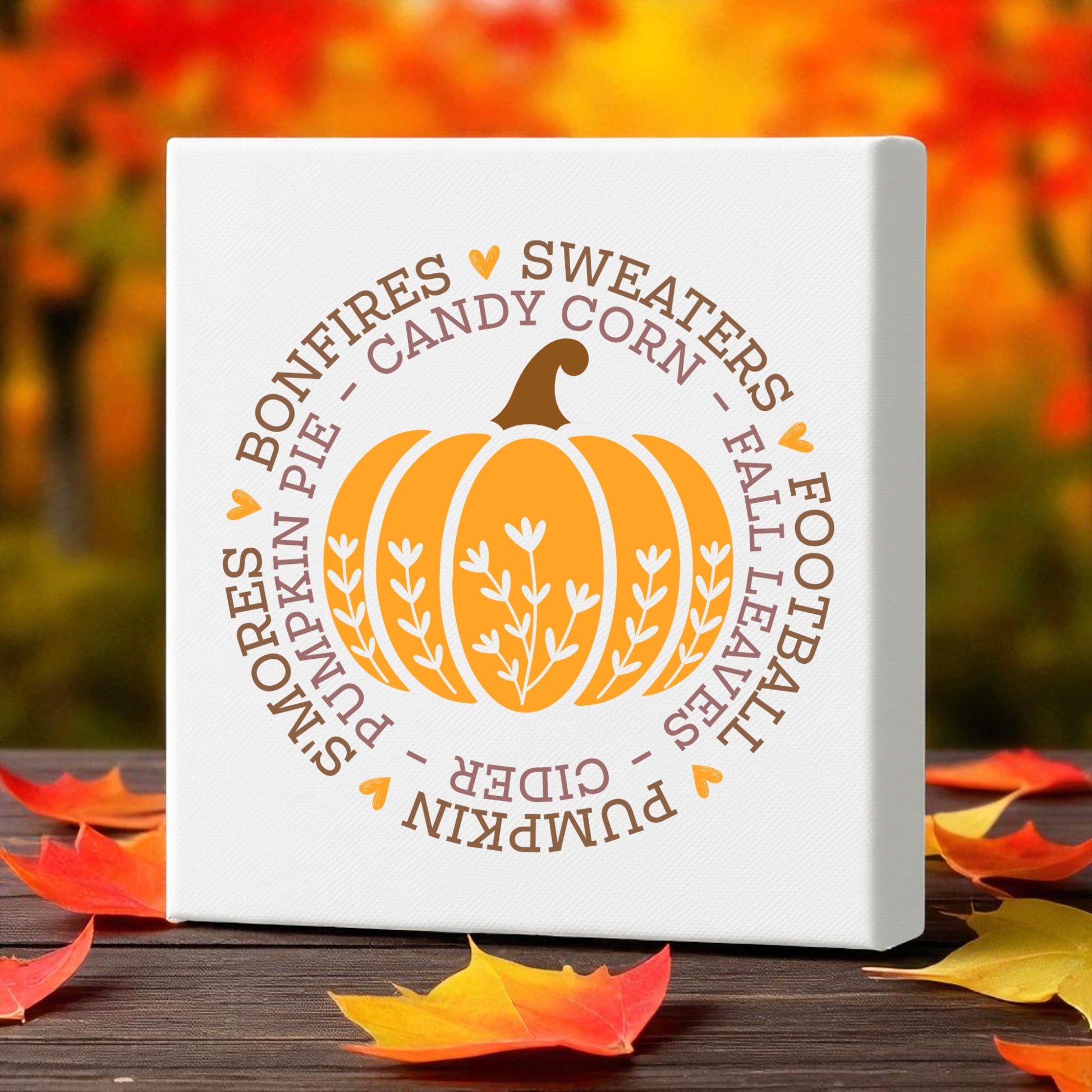 The Fall Pumpkin Canvas by Mirabilia Boutique adds cozy autumn vibes with its orange pumpkin, words like “bonfires” and “pumpkin pie,” and a backdrop of fall foliage. This 8x8 wall art makes perfect seasonal decor for any space.