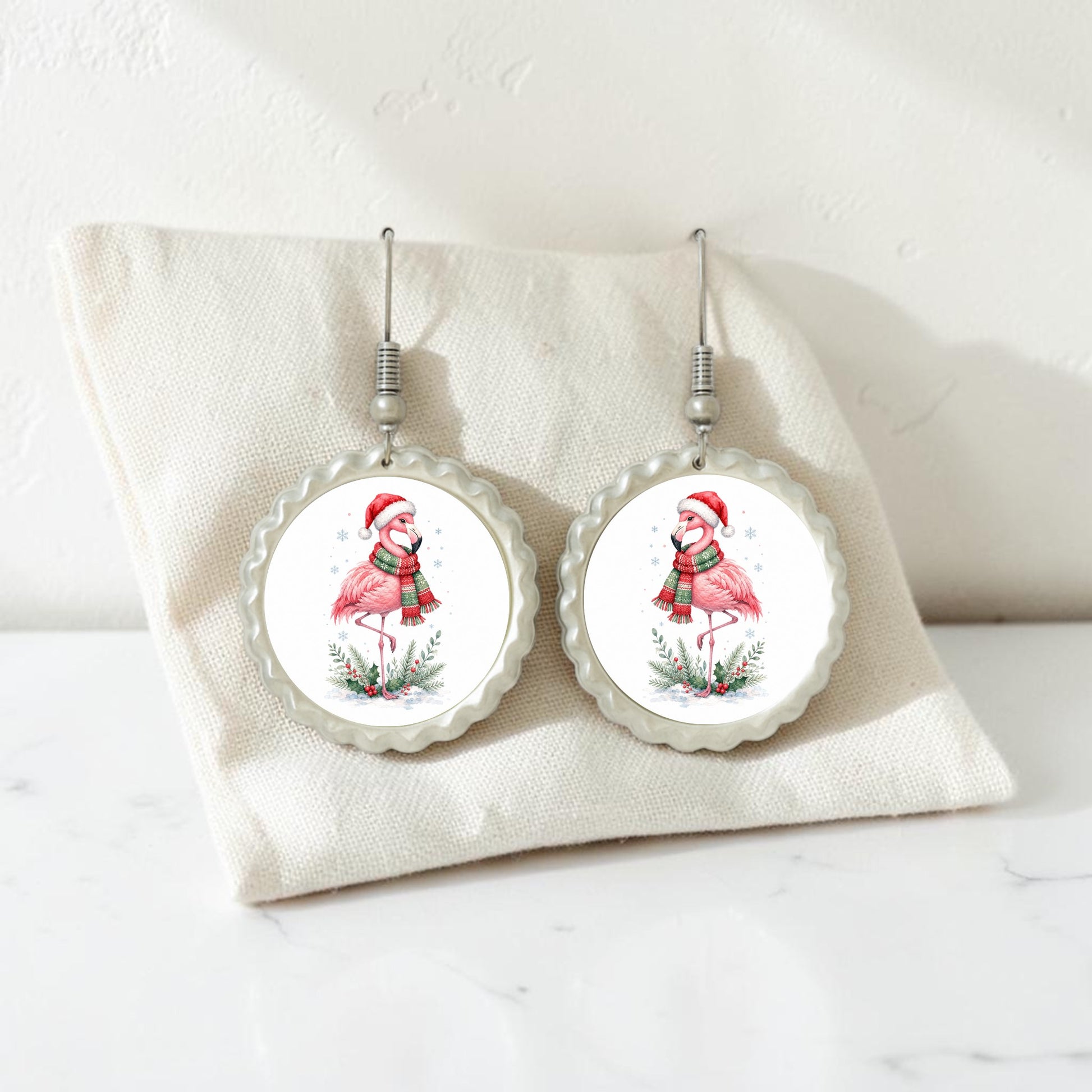 Add a playful holiday flair to your style with the Festive Flamingo Earrings | Winter Bird Jewelry from Mirabilia Boutique. This handcrafted pair features round earrings depicting flamingos in Santa hats and scarves, beautifully displayed on a cream fabric pouch against a white background—perfect for bringing fun Christmas spirit to any look.