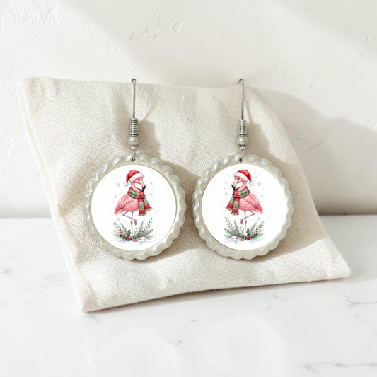 Add a playful holiday flair to your style with the Festive Flamingo Earrings | Winter Bird Jewelry from Mirabilia Boutique. This handcrafted pair features round earrings depicting flamingos in Santa hats and scarves, beautifully displayed on a cream fabric pouch against a white background—perfect for bringing fun Christmas spirit to any look.