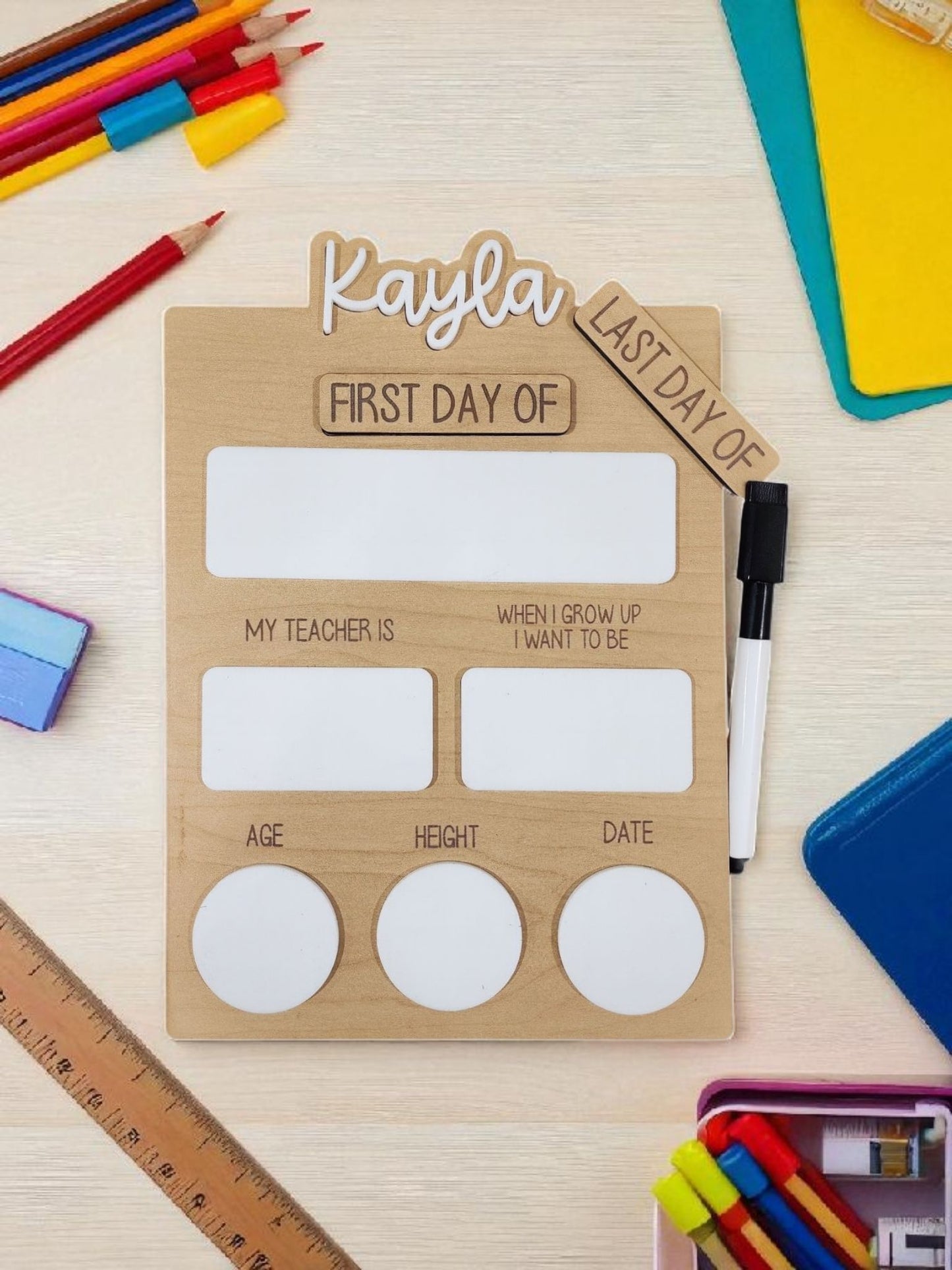 The Mirabilia Boutique Reusable School Board is a dry-erase First & Last Day of School Sign with spaces for name, teacher, aspiration, age, height, and date—ideal for memorable school photos. Dry erase marker included; decorated with colorful school supplies.