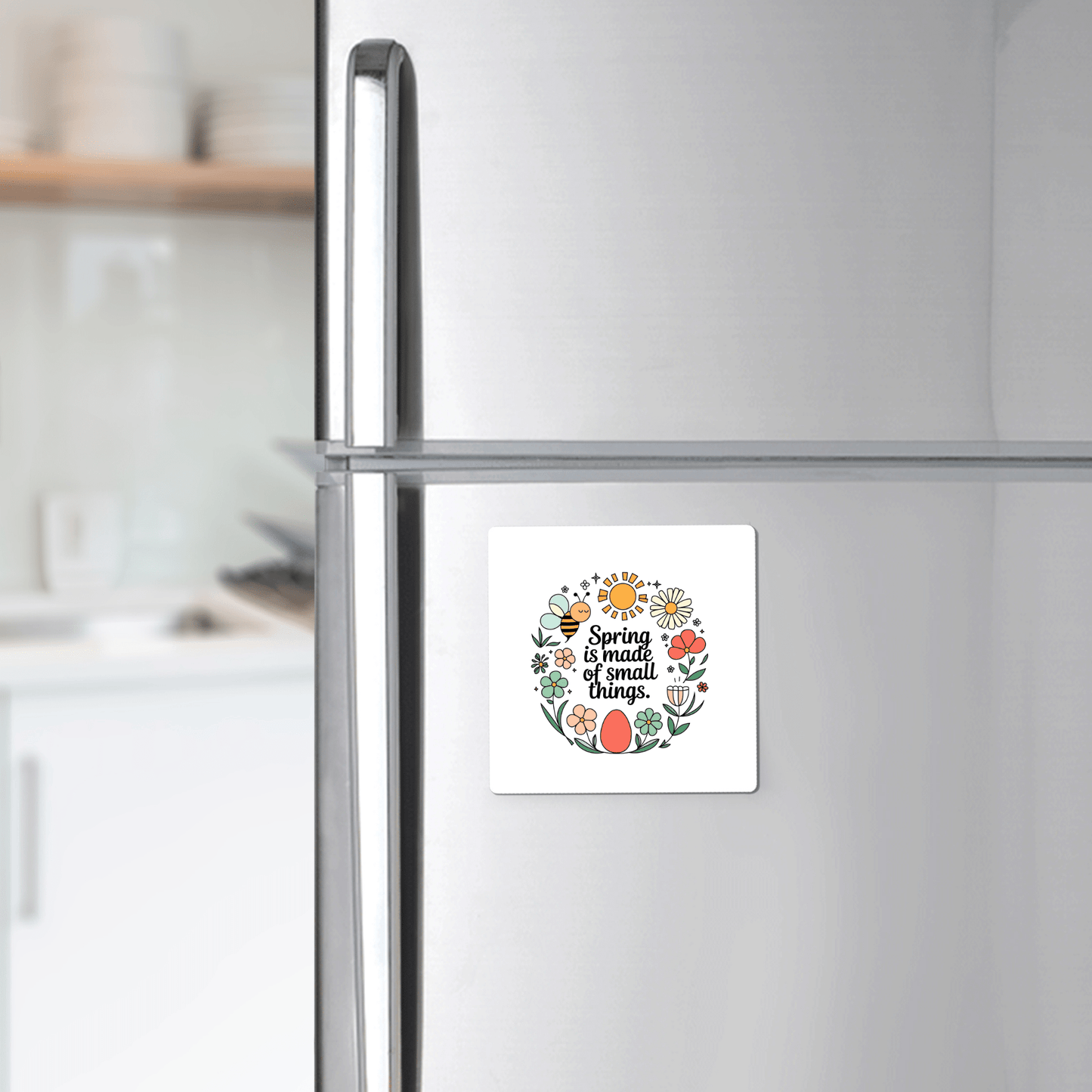 In a bright, modern kitchen, a Mirabilia Boutique "Spring Is Made of Small Things Floral Magnet" decorates the refrigerator door with its colorful flowers and leaves.