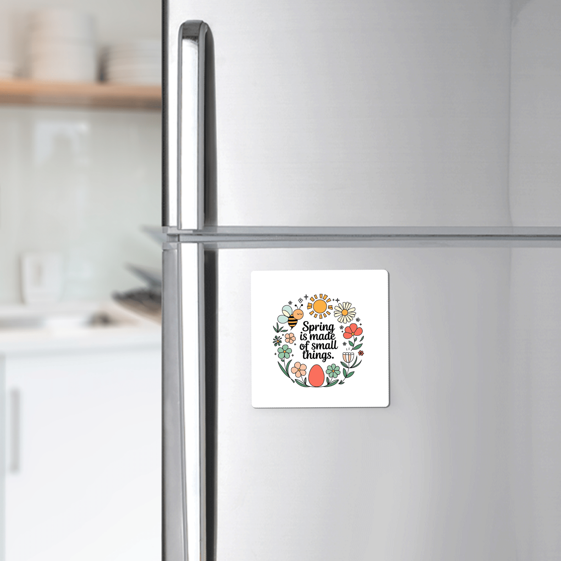 In a bright, modern kitchen, a Mirabilia Boutique "Spring Is Made of Small Things Floral Magnet" decorates the refrigerator door with its colorful flowers and leaves.
