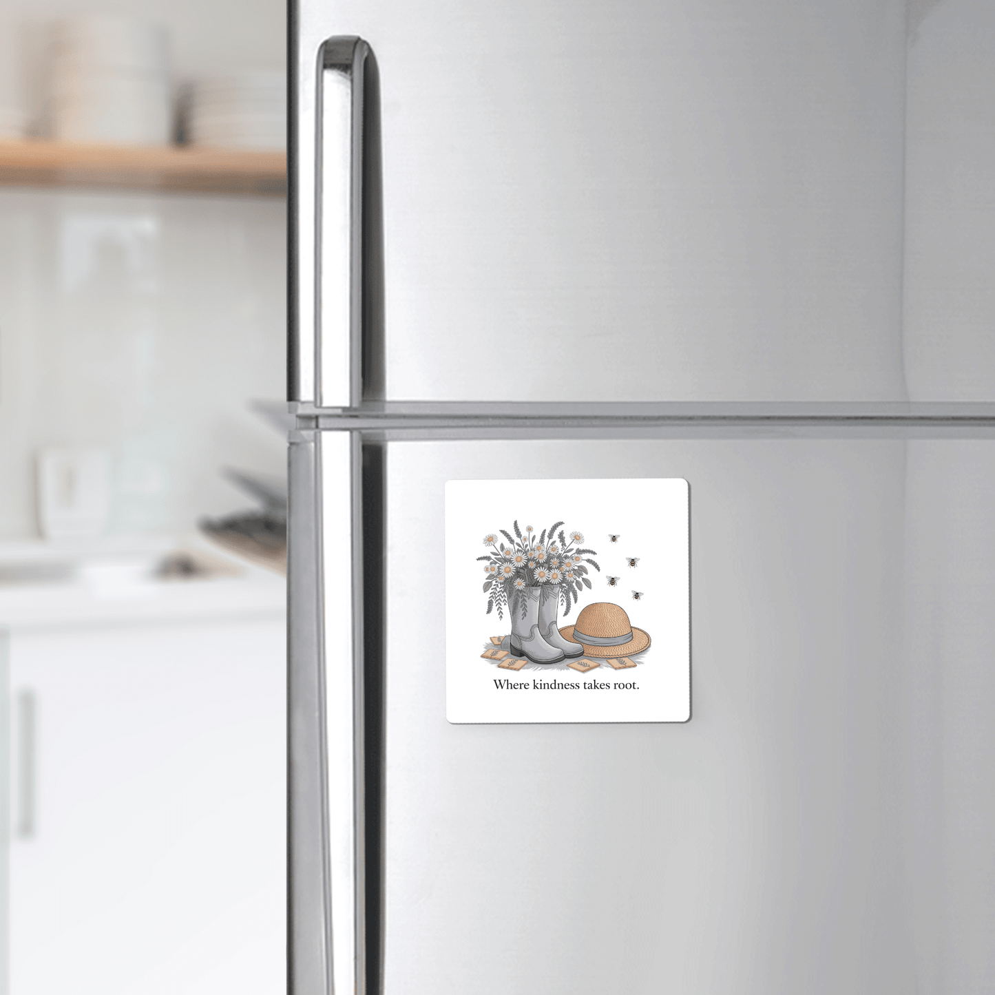 The Mirabilia Boutique Kindness Garden Magnet features floral boots, wildflowers, a straw hat, and bees with the quote "Where kindness takes root." The magnet adds charm to any refrigerator or kitchen decor.