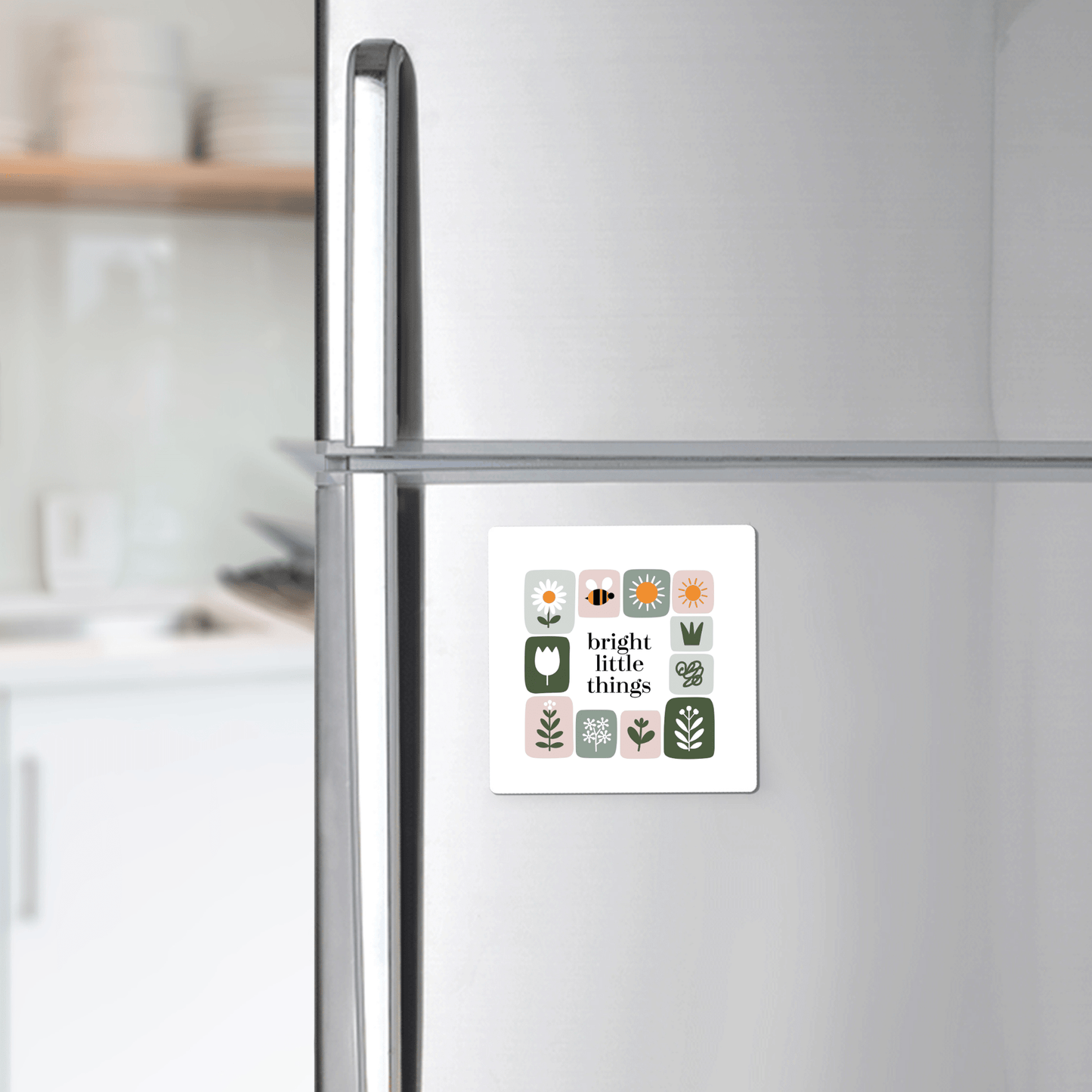 The Bright Little Things Floral Grid Magnet by Mirabilia Boutique adds cheerful decor with its colorful plant and flower icons and text to any stainless steel fridge in a modern kitchen.