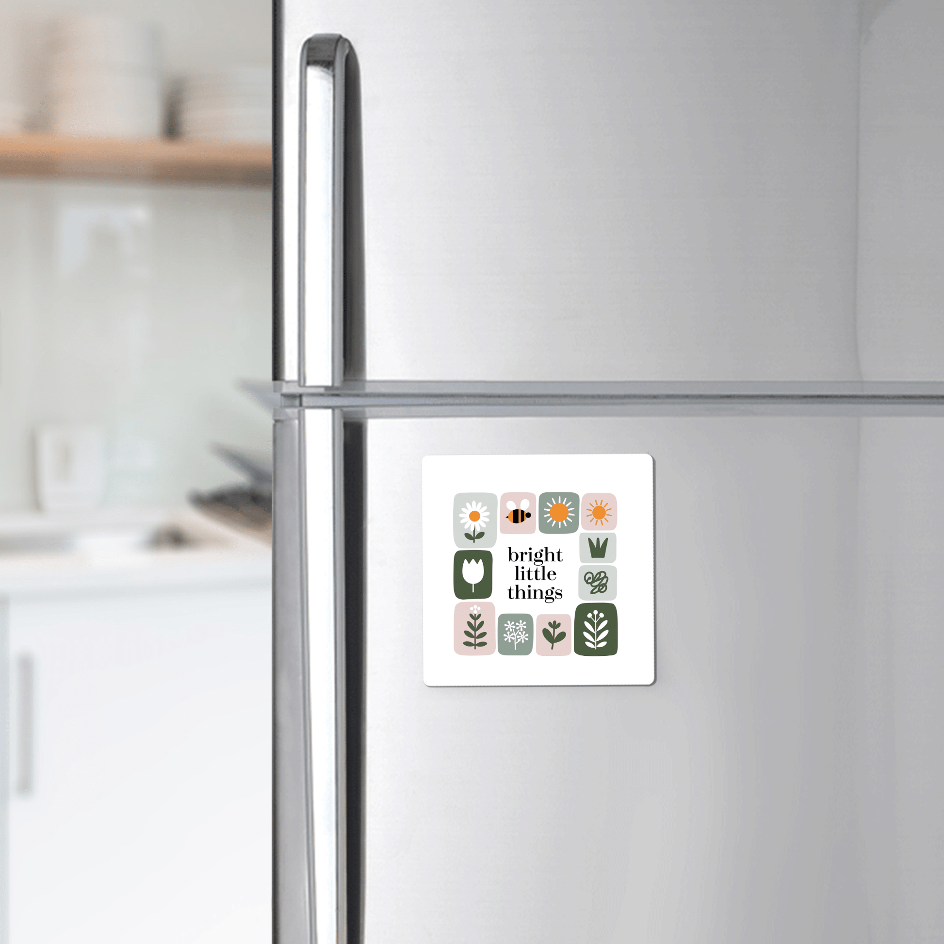The Bright Little Things Floral Grid Magnet by Mirabilia Boutique adds cheerful decor with its colorful plant and flower icons and text to any stainless steel fridge in a modern kitchen.
