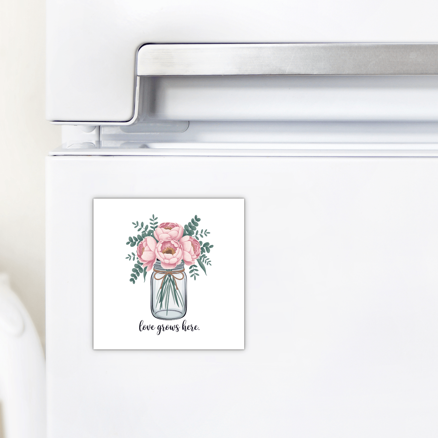 The "Love Grows Here Floral Magnet" by Mirabilia Boutique adds farmhouse charm with pink flowers in a jar and sweet text—perfect for brightening your fridge or gifting as a thoughtful housewarming present.