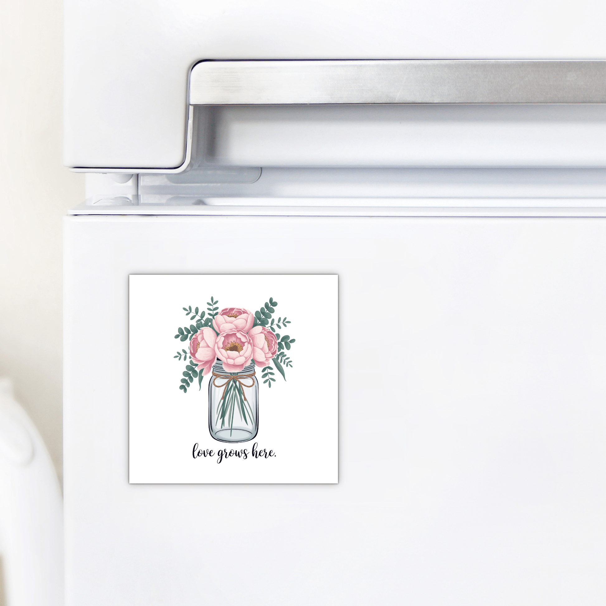The "Love Grows Here Floral Magnet" by Mirabilia Boutique adds farmhouse charm with pink flowers in a jar and sweet text—perfect for brightening your fridge or gifting as a thoughtful housewarming present.