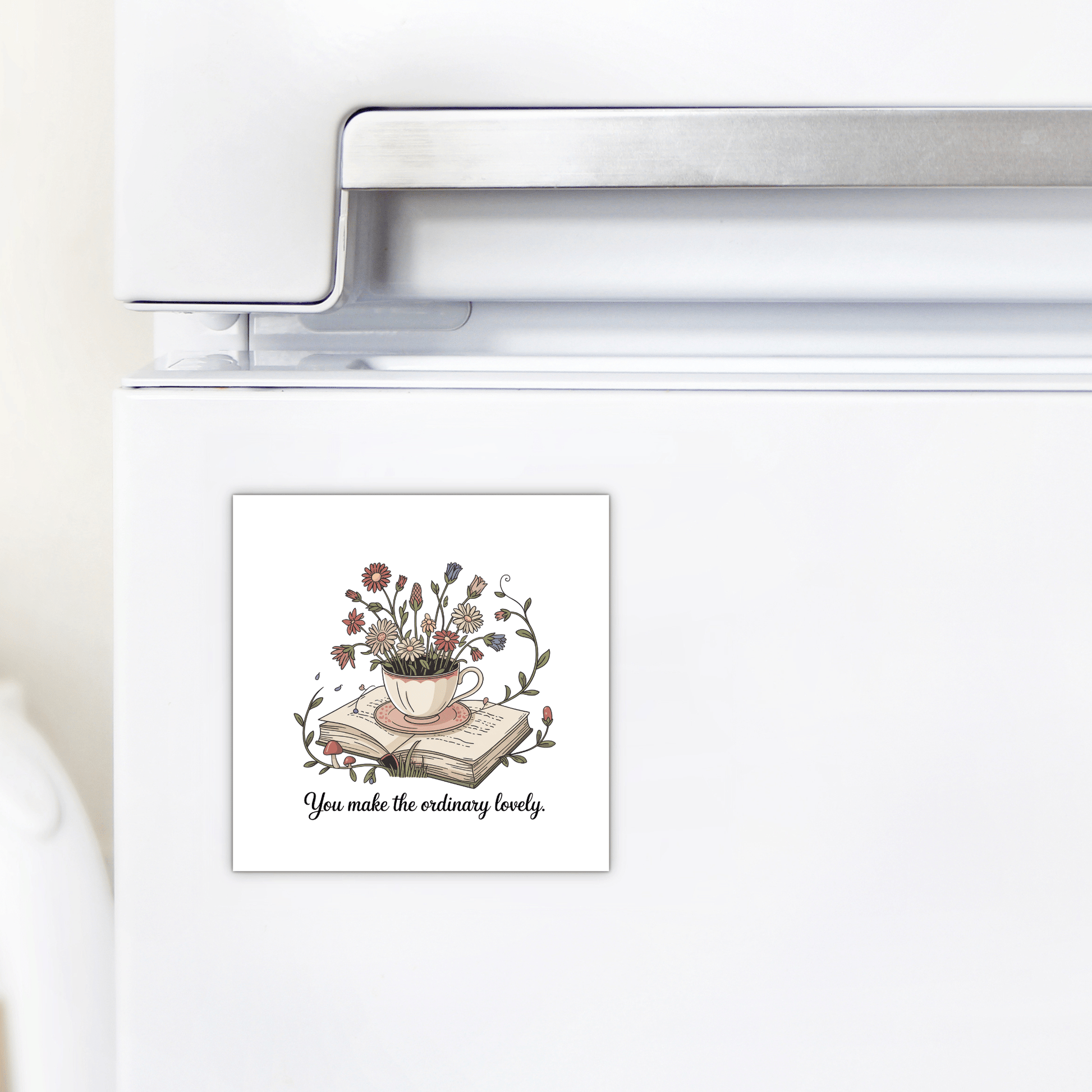 The Floral Teacup Book Magnet by Mirabilia Boutique features a teacup with flowers and books and the phrase “You Make the Ordinary Lovely”—a lovely, inspirational gift to brighten any kitchen fridge.