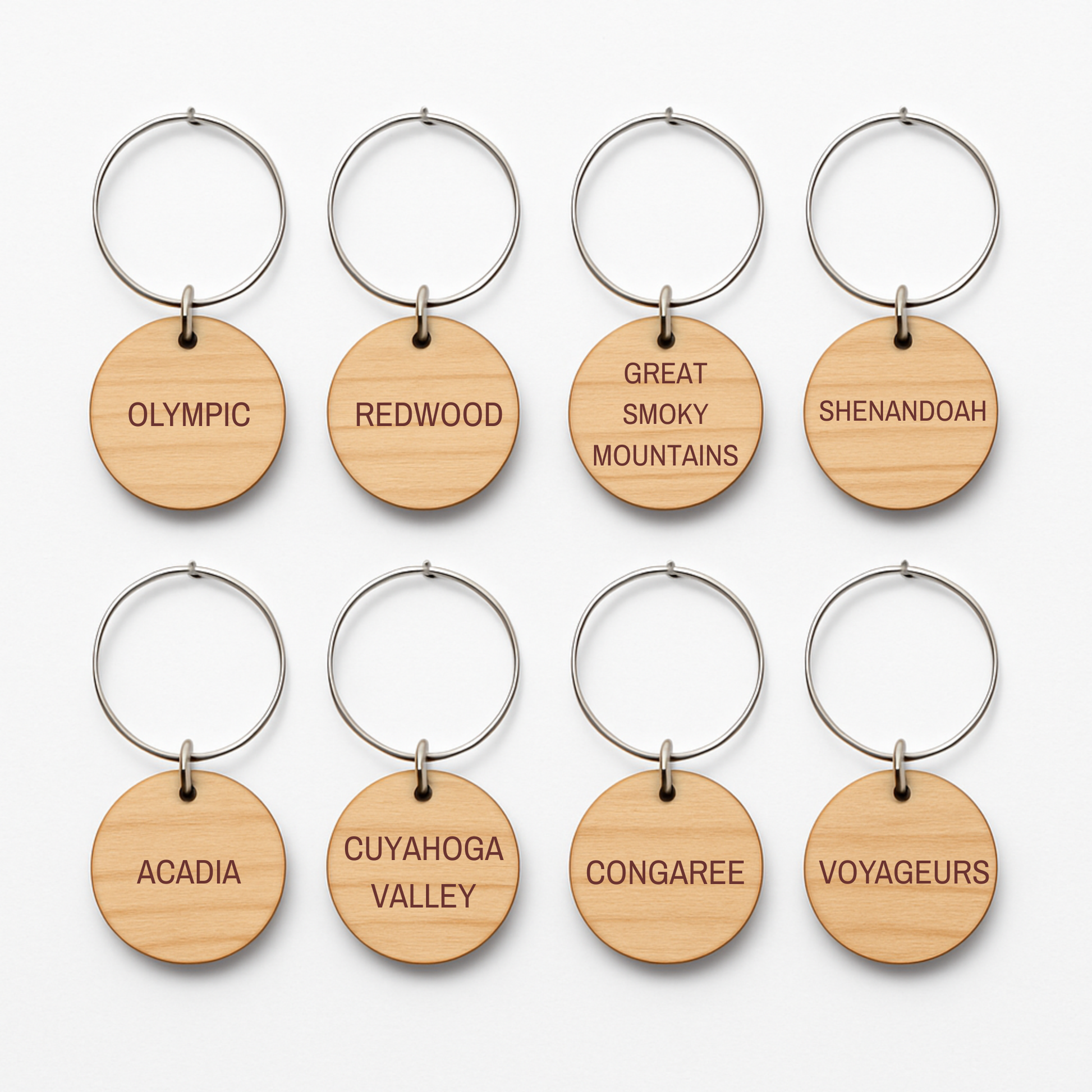 Eight Forest And Fog Wine Charms by Mirabilia Boutique are arranged in two rows, each featuring a U.S. national park’s name—perfect for nature lovers who admire woodland landscapes like Olympic, Redwood, Shenandoah, and more.