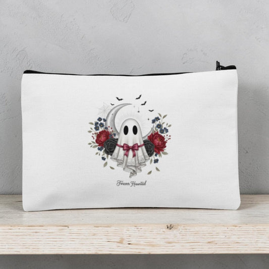 The Forever Haunted Makeup Bag | Gothic Ghost Pouch by Mirabilia Boutique features a white zippered design decorated with an adorable ghost wearing a floral crown and bowtie, surrounded by red and black roses, leaves, and bats. The phrase “Boo Yourself” appears beneath the ghost. Perfect as a spooky season accessory or Halloween makeup bag, this gothic cosmetic pouch is displayed on a light wooden shelf.