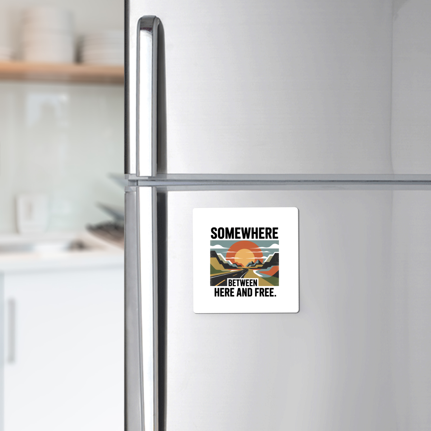 The Mirabilia Boutique "Somewhere Between Here and Free" Magnet features a sunset and mountains design—perfect for adding adventure to your fridge décor.