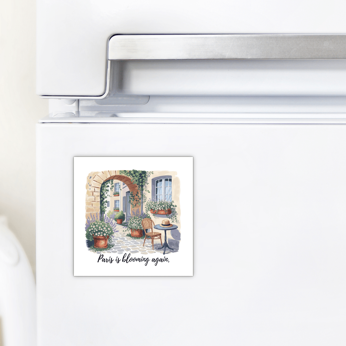 The Mirabilia Boutique Paris Is Blooming Again – Spring Courtyard Magnet features a charming Parisian courtyard scene with flowers, plants, table, and chairs, plus the text "Paris is blooming again"—perfect for spring kitchen décor.