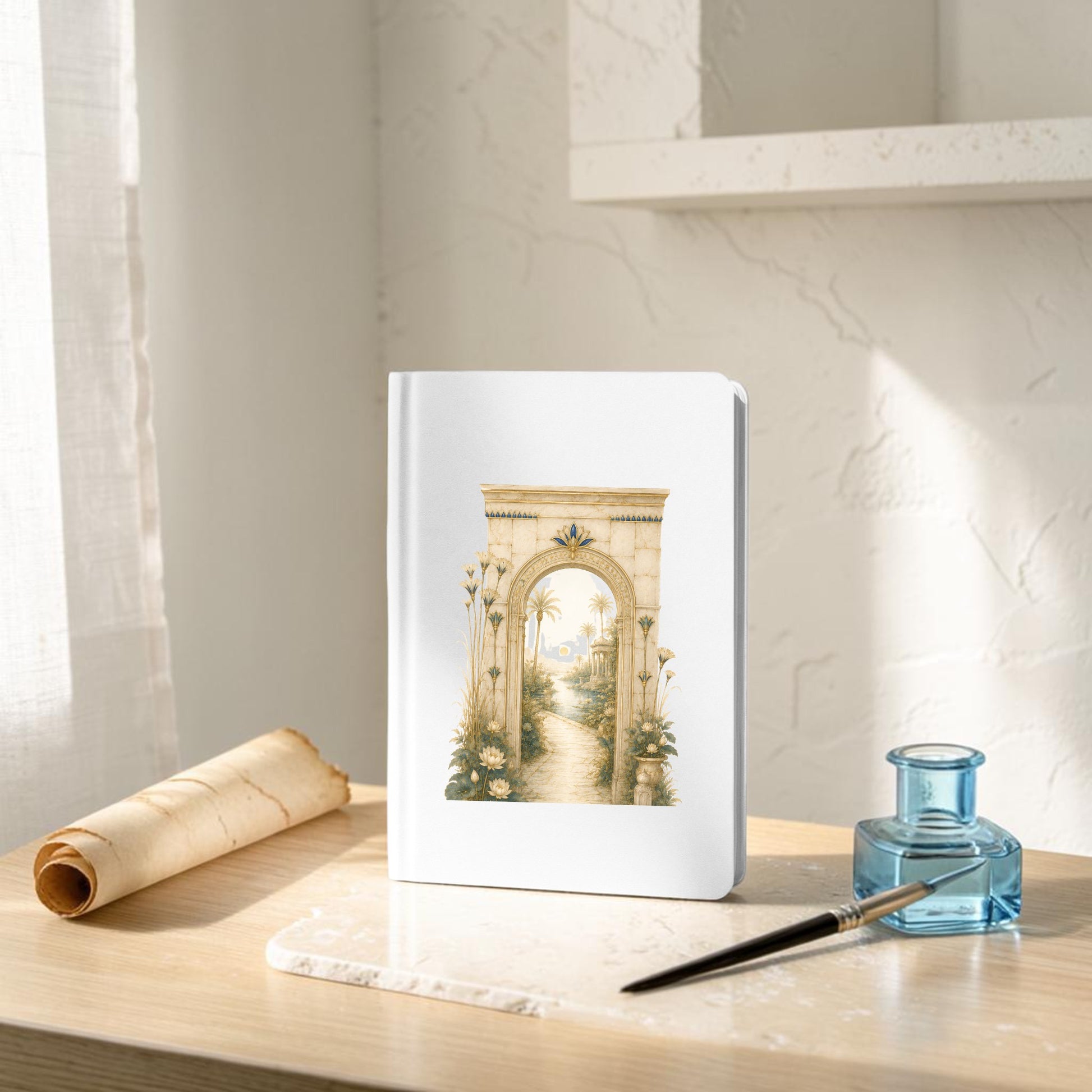 A Garden Path Journal | Ancient Egyptian Inspired Notebook from Mirabilia Boutique’s Lapis & Lotus Collection, featuring an illustrated archway and garden path on the cover, rests on a sunlit desk alongside a scroll, ink bottle, and quill. Soft light reveals shelves and a window in the background.