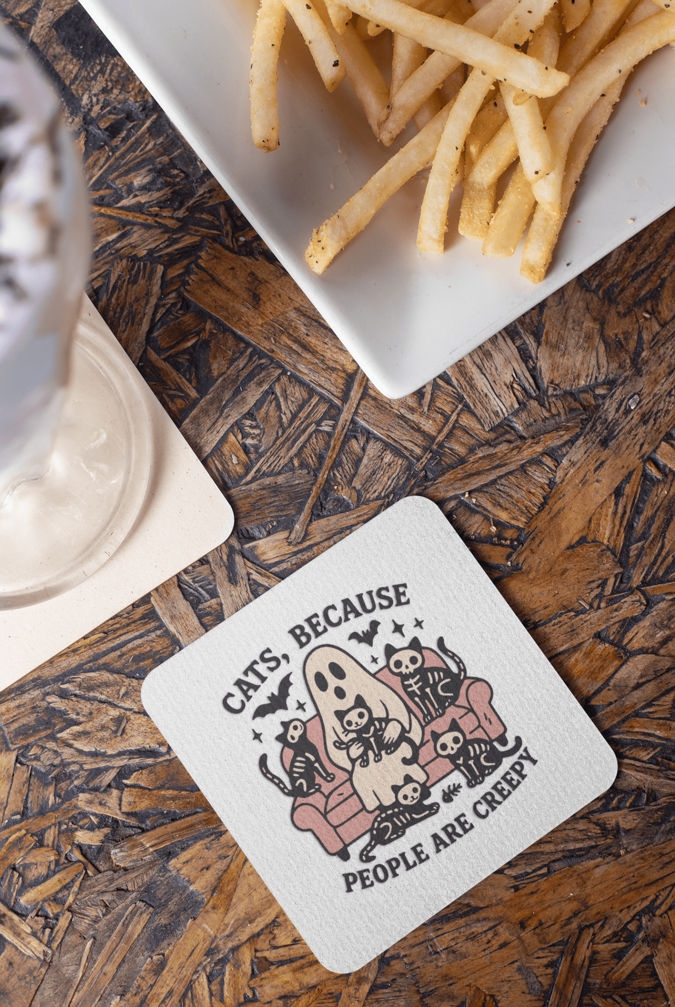 The Mirabilia Boutique Funny Ghost Cat Coaster features a quirky cartoon ghost and cats with the phrase "Cats Because People Are Creepy." Perfect for cat lovers or gothic decor, it adds whimsical charm to any table.