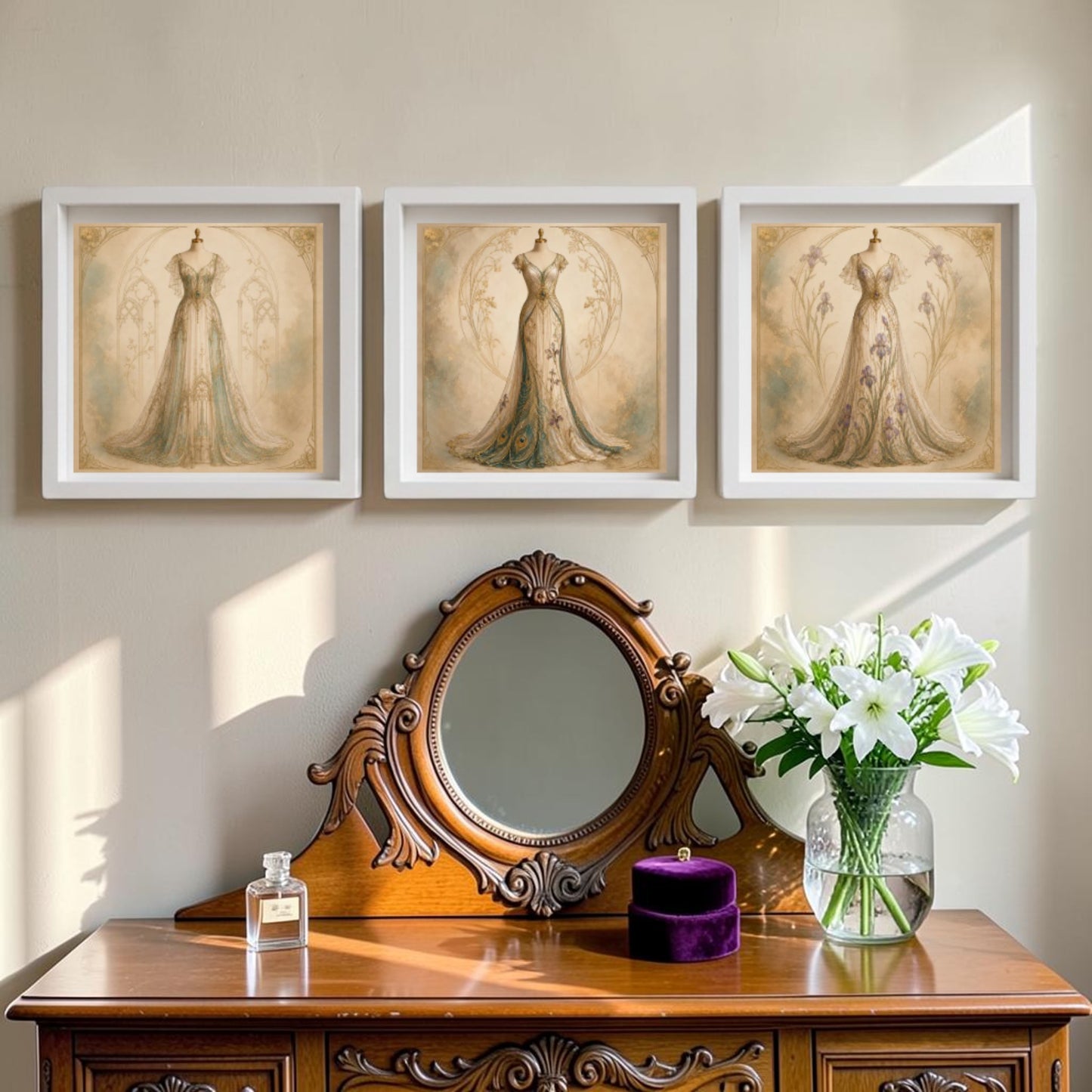 Below three framed Mirabilia Boutique Conservatory Collection | Curated Couture Artworks hung on a light wall stands a wooden vanity, adorned with a round mirror, perfume bottle, and a vase of white lilies.