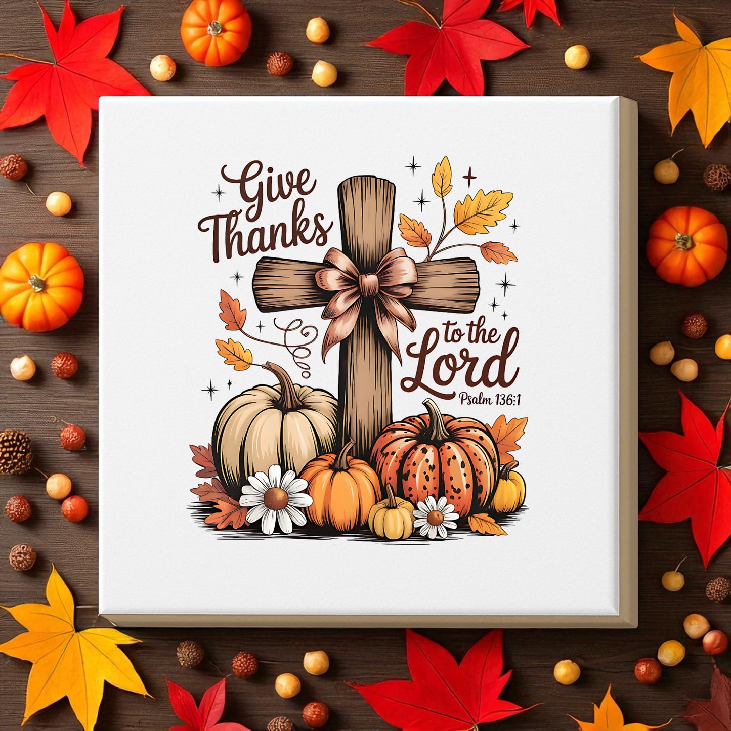 The Thanksgiving Canvas by Mirabilia Boutique features a wooden cross, pumpkins, leaves, and flowers with the verse “Give Thanks to the Lord. Psalm 136:1”—a perfect fall décor piece for Thanksgiving.