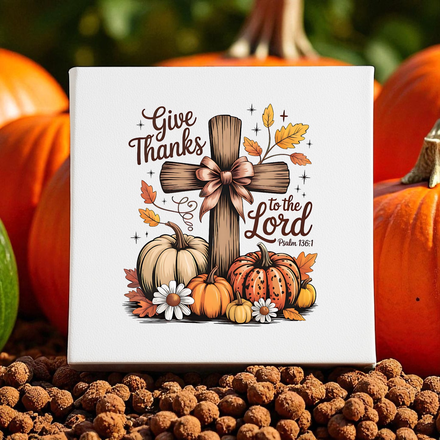The Mirabilia Boutique Thanksgiving Canvas features a wooden cross with bow, autumn leaves, and pumpkins. This fall decor reads "Give Thanks to the Lord Psalm 136:1," perfect for your seasonal display.