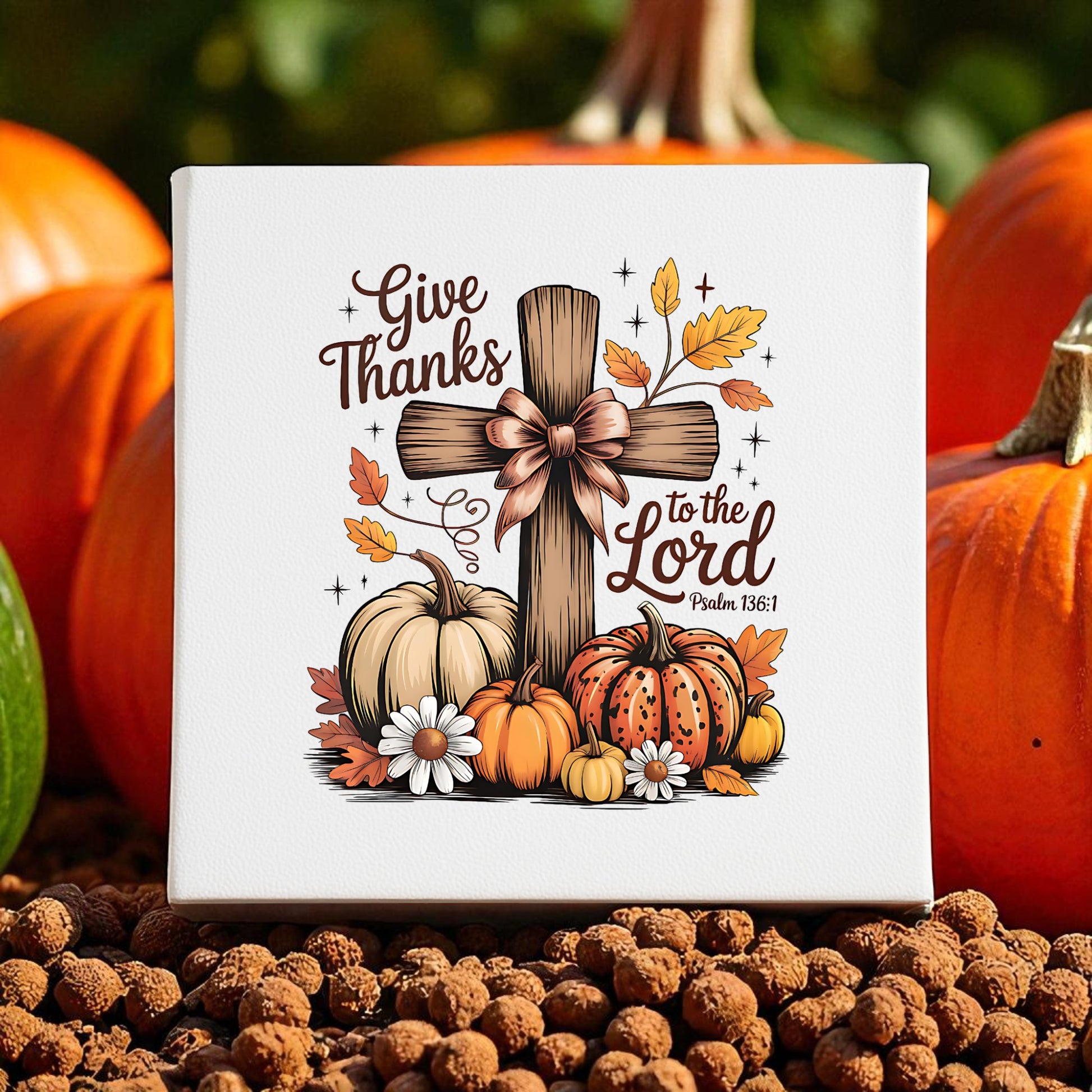 The Mirabilia Boutique Thanksgiving Canvas features a wooden cross with bow, autumn leaves, and pumpkins. This fall decor reads "Give Thanks to the Lord Psalm 136:1," perfect for your seasonal display.