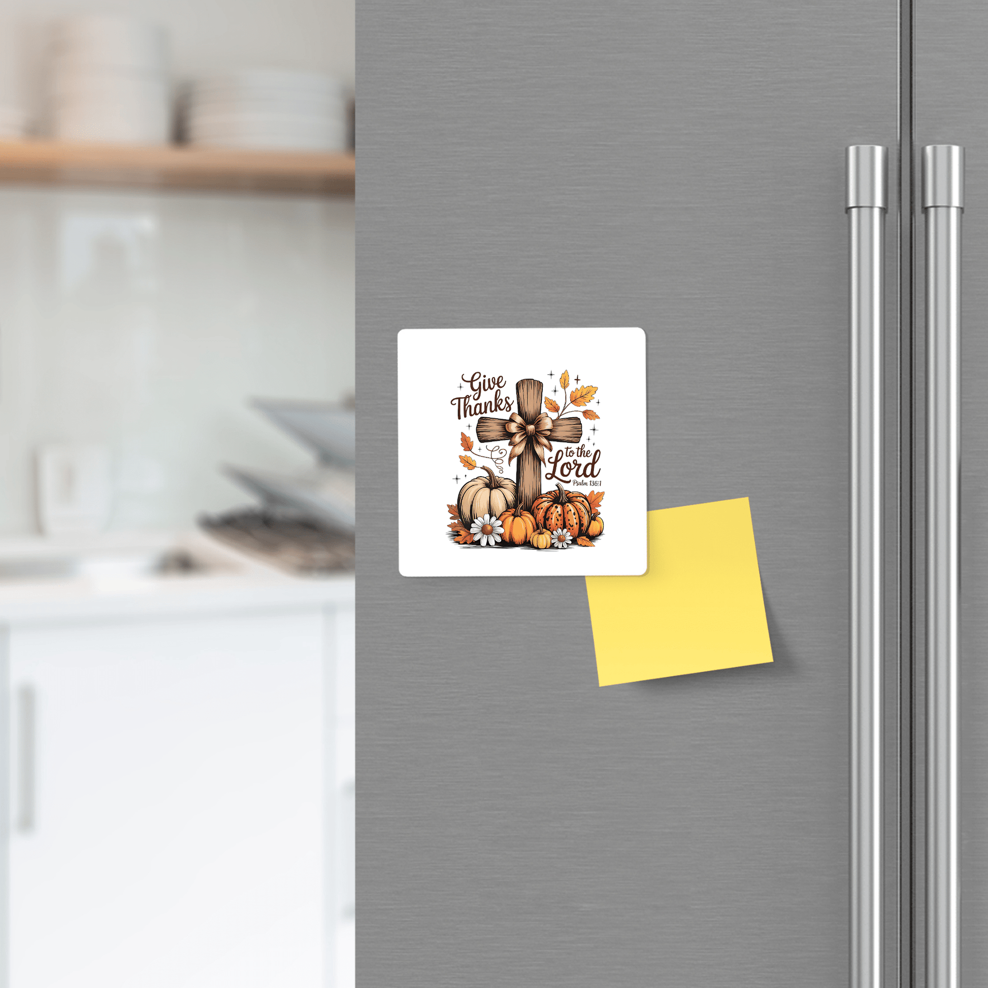 The Mirabilia Boutique "Give Thanks Fall Magnet" features a Psalm 136:1 cross, pumpkins, and autumn leaves—Christian fridge decor perfect for Thanksgiving gifting. A yellow sticky note sits beneath this festive magnet.