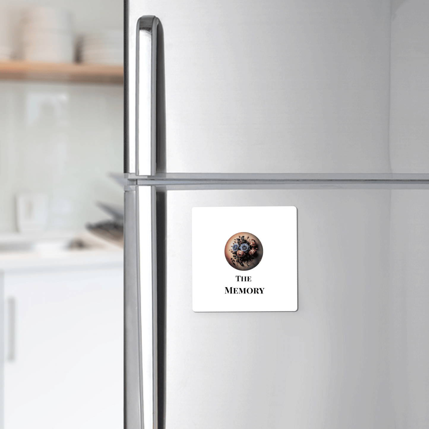 A silver fridge features Mirabilia Boutique’s “The Memory” Dead Regency Magnet—a white gothic floral decor piece with a bouquet and “THE MEMORY” text, adding unique minimal gothic style to your kitchen.