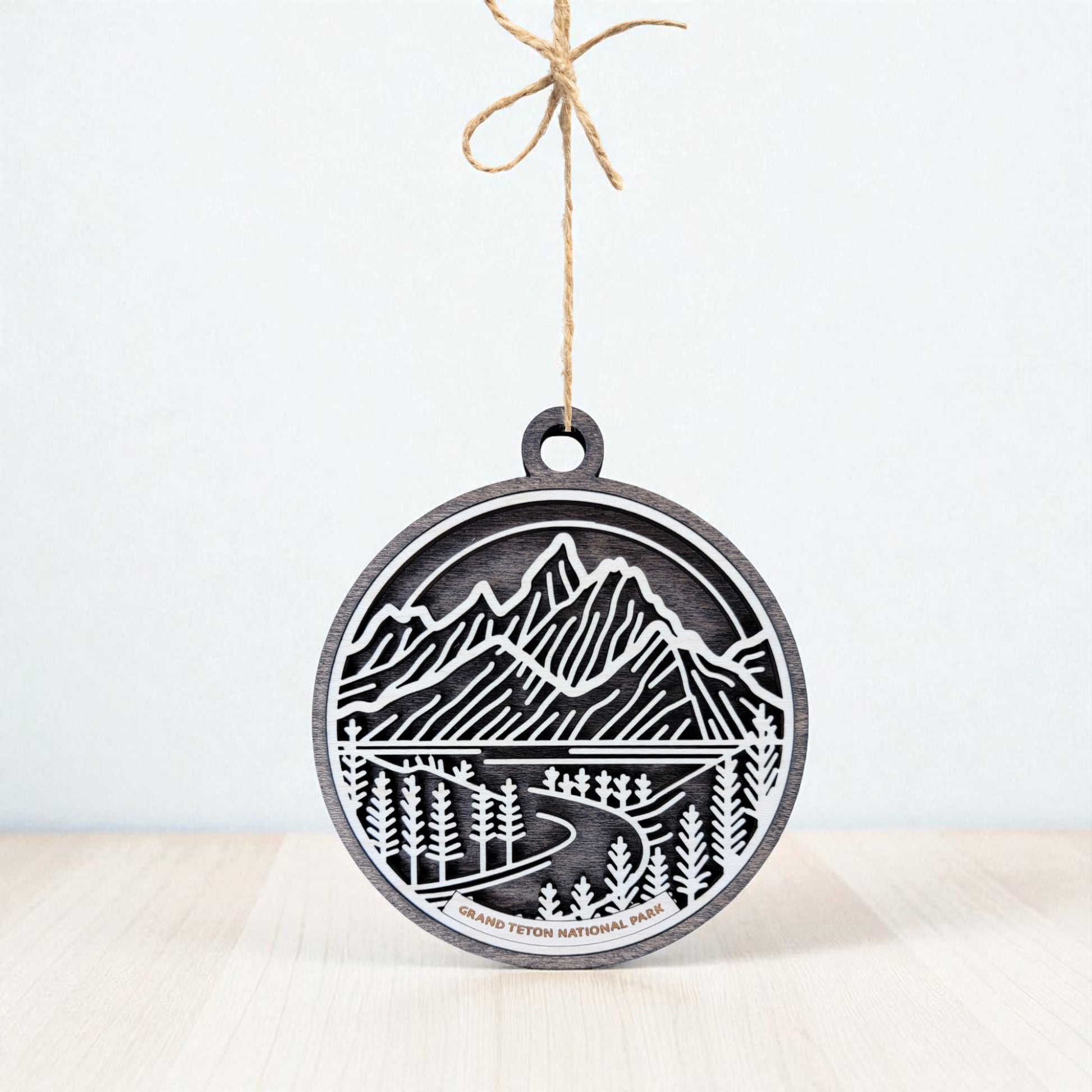 The Grand Teton National Park Ornament by Mirabilia Boutique is a wooden mountain gift with a laser-cut design, twine for hanging, and “Grand Teton National Park” label—ideal as nature-inspired holiday decor.