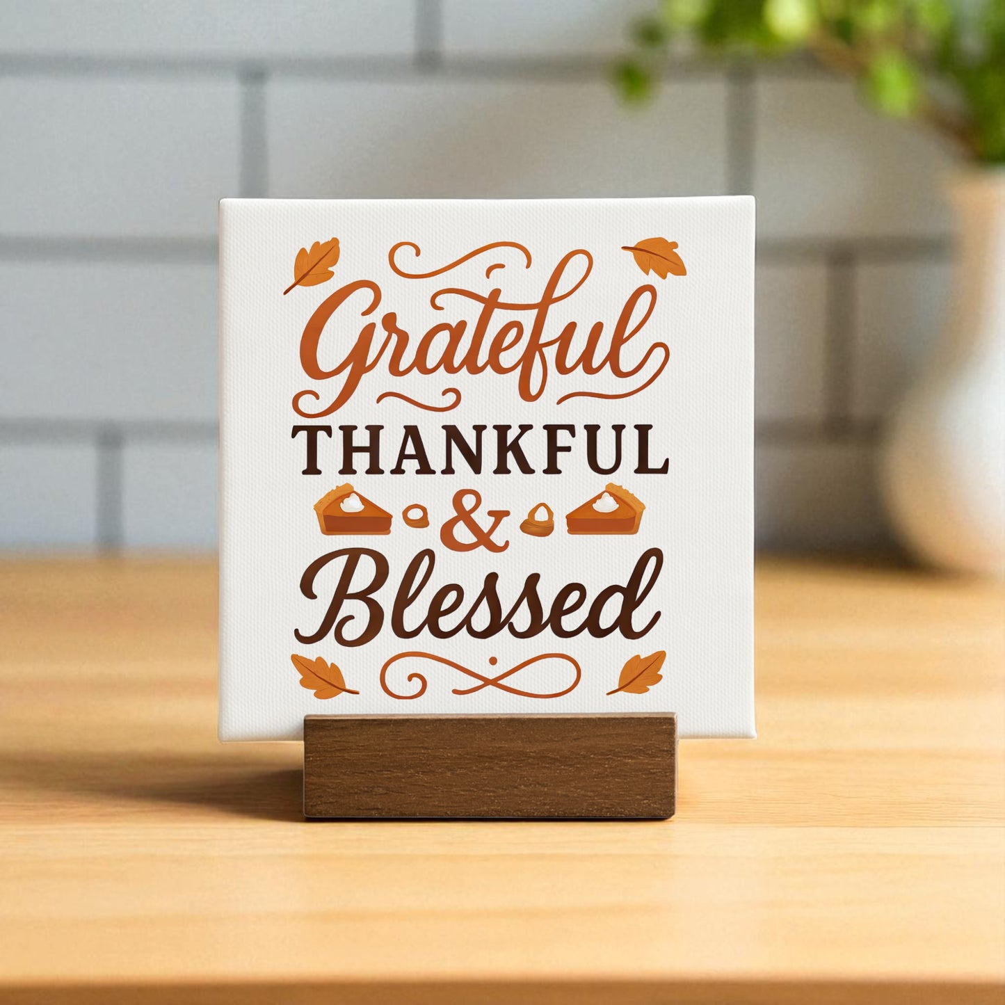 The Grateful Thankful Blessed Mini Sign by Mirabilia Boutique is a fall tabletop decor piece with brown and orange lettering, leaf and pie accents, set on a wooden stand for seasonal charm.
