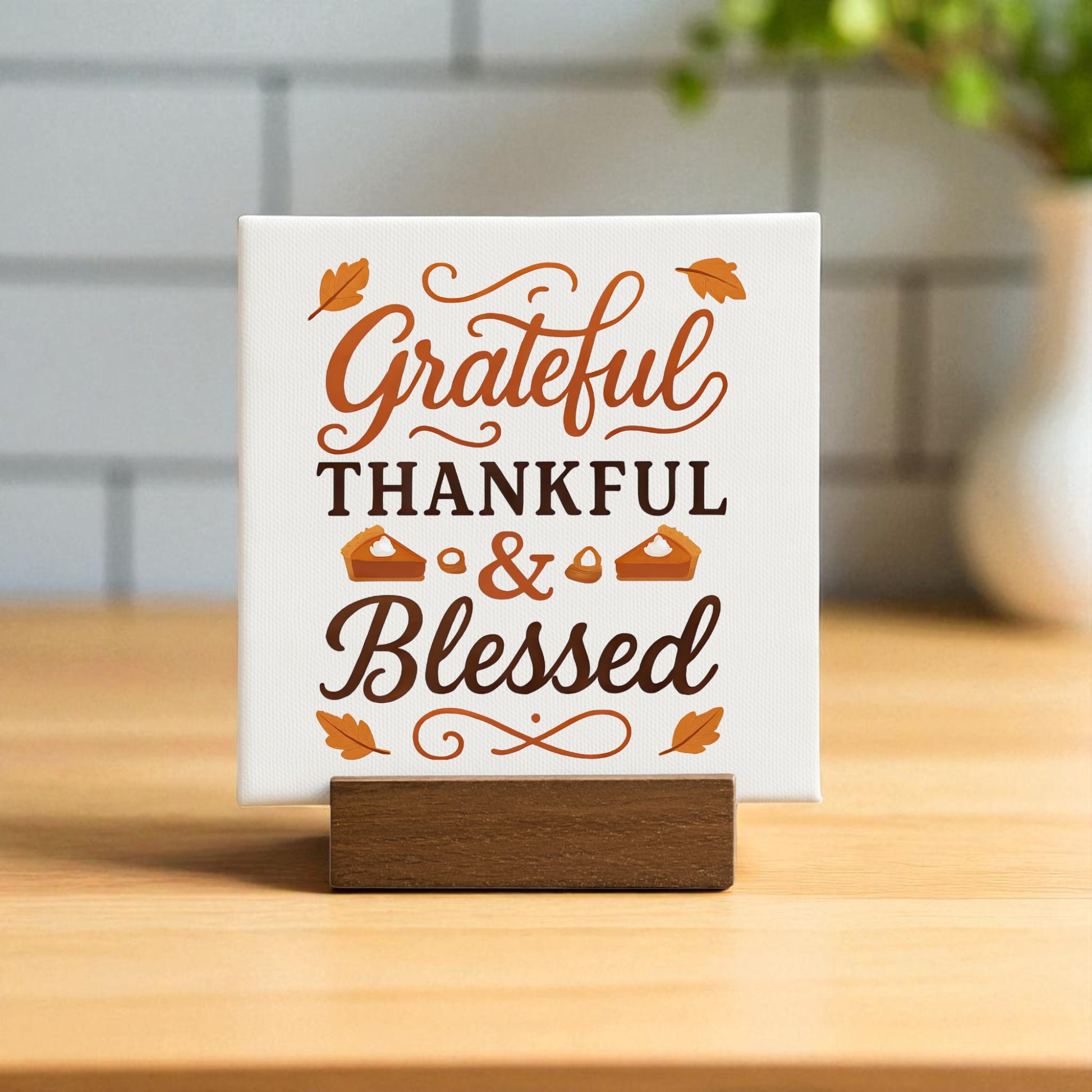 The Grateful Thankful Blessed Mini Sign by Mirabilia Boutique is a fall tabletop decor piece with brown and orange lettering, leaf and pie accents, set on a wooden stand for seasonal charm.