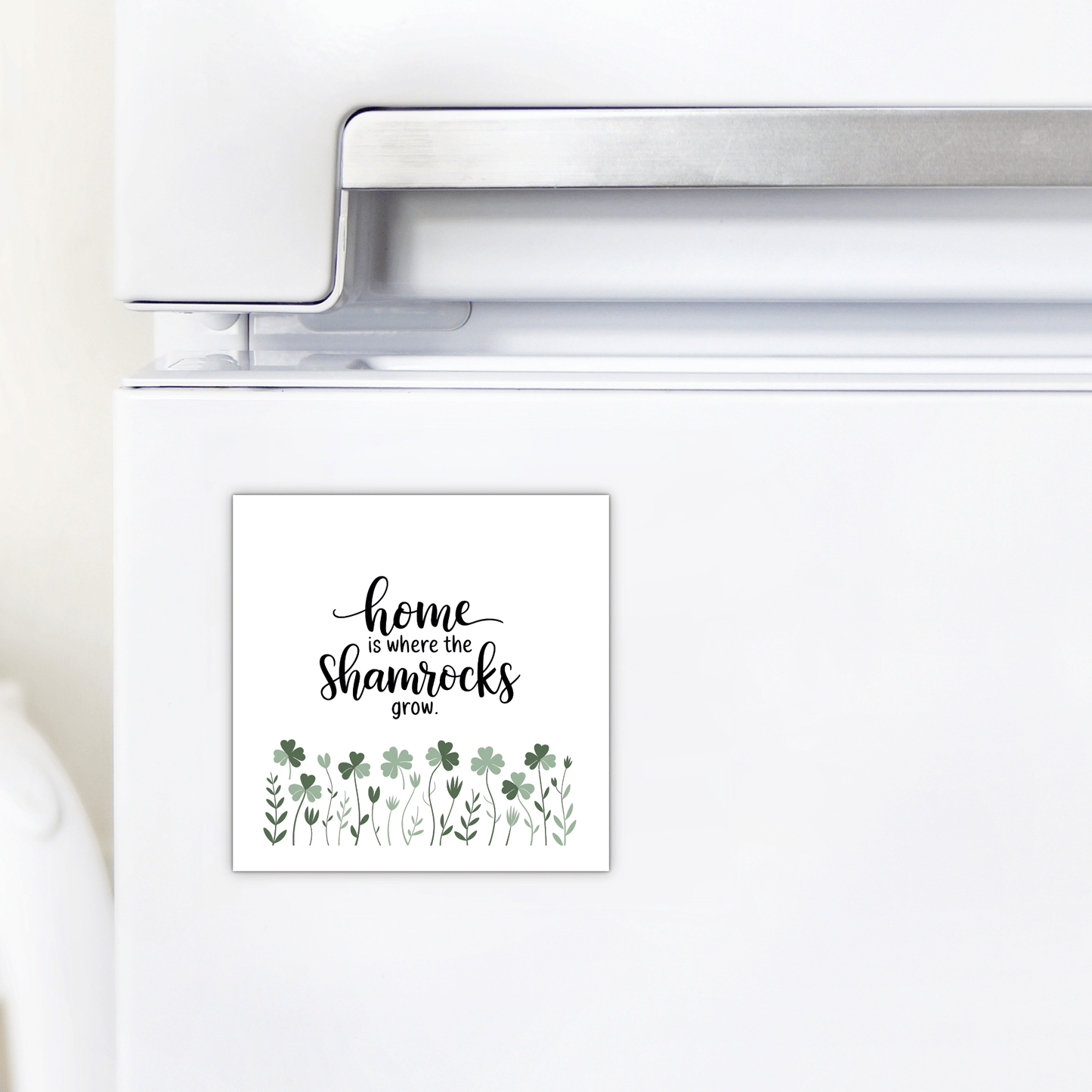 The Mirabilia Boutique "Home Is Where the Shamrocks Grow Magnet" adds a charming touch to any white refrigerator with its square design, green shamrocks, and leafy plants—perfect for Irish-inspired spring home decor.