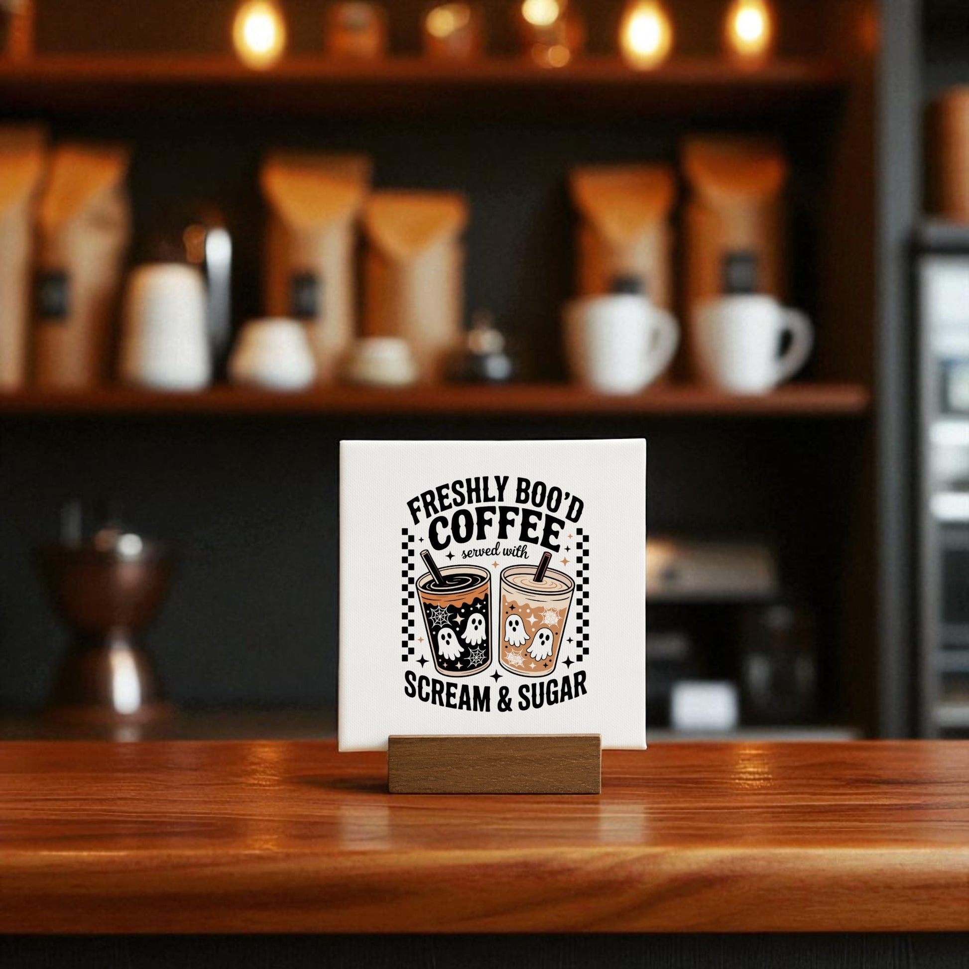 The Mirabilia Boutique Halloween Coffee Bar Sign | Freshly Boo’d Coffee | Mini 4x4 Decor sits on a wooden counter with ghost coffee decor and three spooky cups, against a softly blurred, cozy coffee shop background.