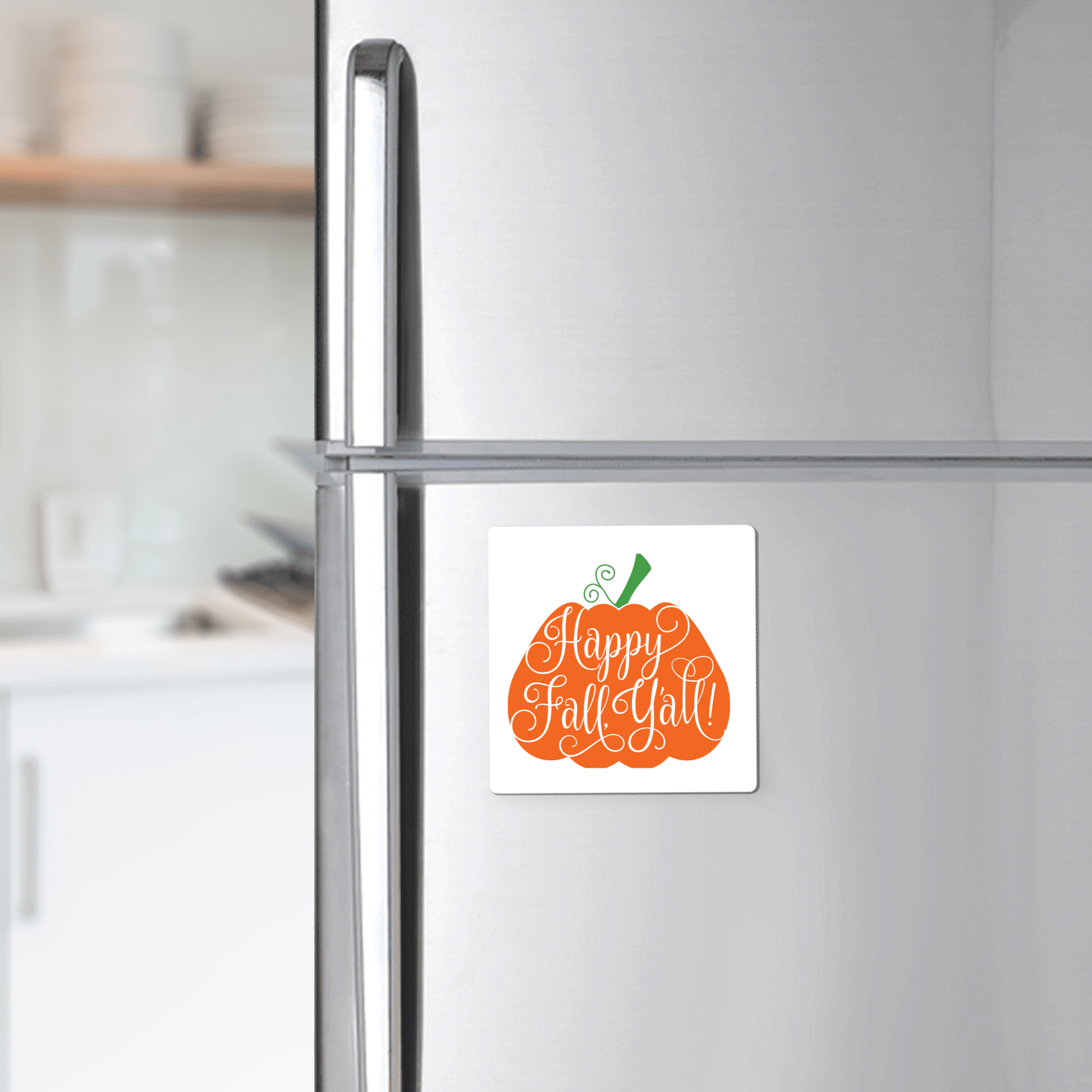 A Mirabilia Boutique Happy Fall Y’all Magnet—a pumpkin-shaped fall decor piece with hand-lettered script—adds charm to a stainless steel fridge, creating a cozy autumn vibe in your kitchen.