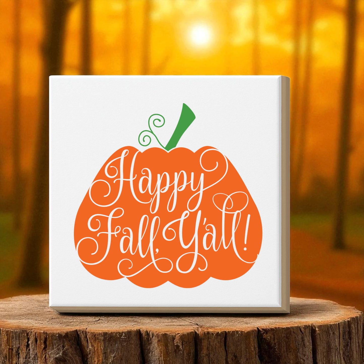 The "Happy Fall Y’all Pumpkin Wall Art" by Mirabilia Boutique sits on a tree stump, its cursive greeting and pumpkin design bathed in golden sunlight, bringing a touch of southern charm to cozy autumn home decor.