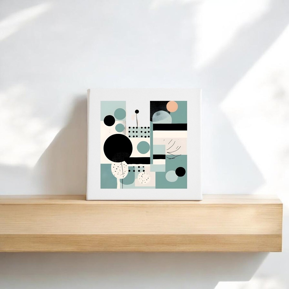 The Harbor Morning Mid Century Modern Canvas by Mirabilia Boutique, featuring muted green, peach, black, and cream geometric abstract art, rests on a light wooden shelf with natural light and soft shadows on the white wall behind.