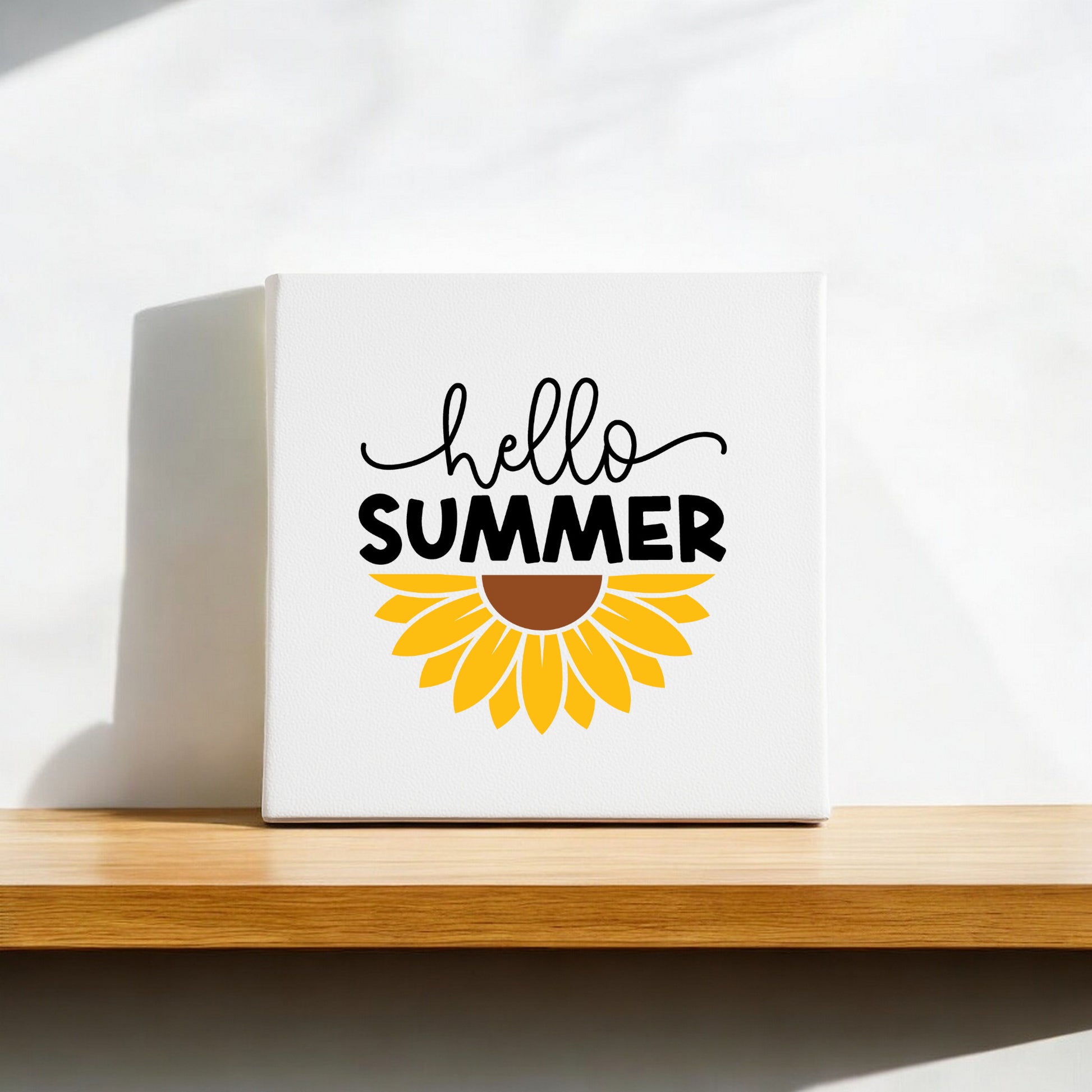 The Hello Summer Sunflower Canvas Sign – 8x8 Wall Art by Mirabilia Boutique sits on a wooden shelf, with “hello SUMMER” and a sunflower graphic, making this wall decor ideal for farmhouse styling.