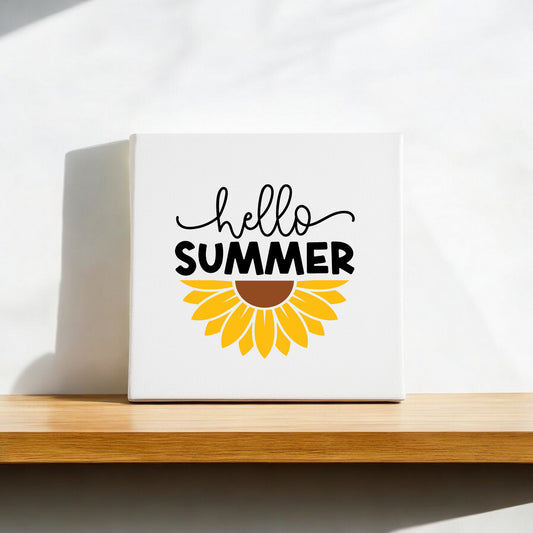 The Hello Summer Sunflower Canvas Sign – 8x8 Wall Art by Mirabilia Boutique sits on a wooden shelf, with “hello SUMMER” and a sunflower graphic, making this wall decor ideal for farmhouse styling.