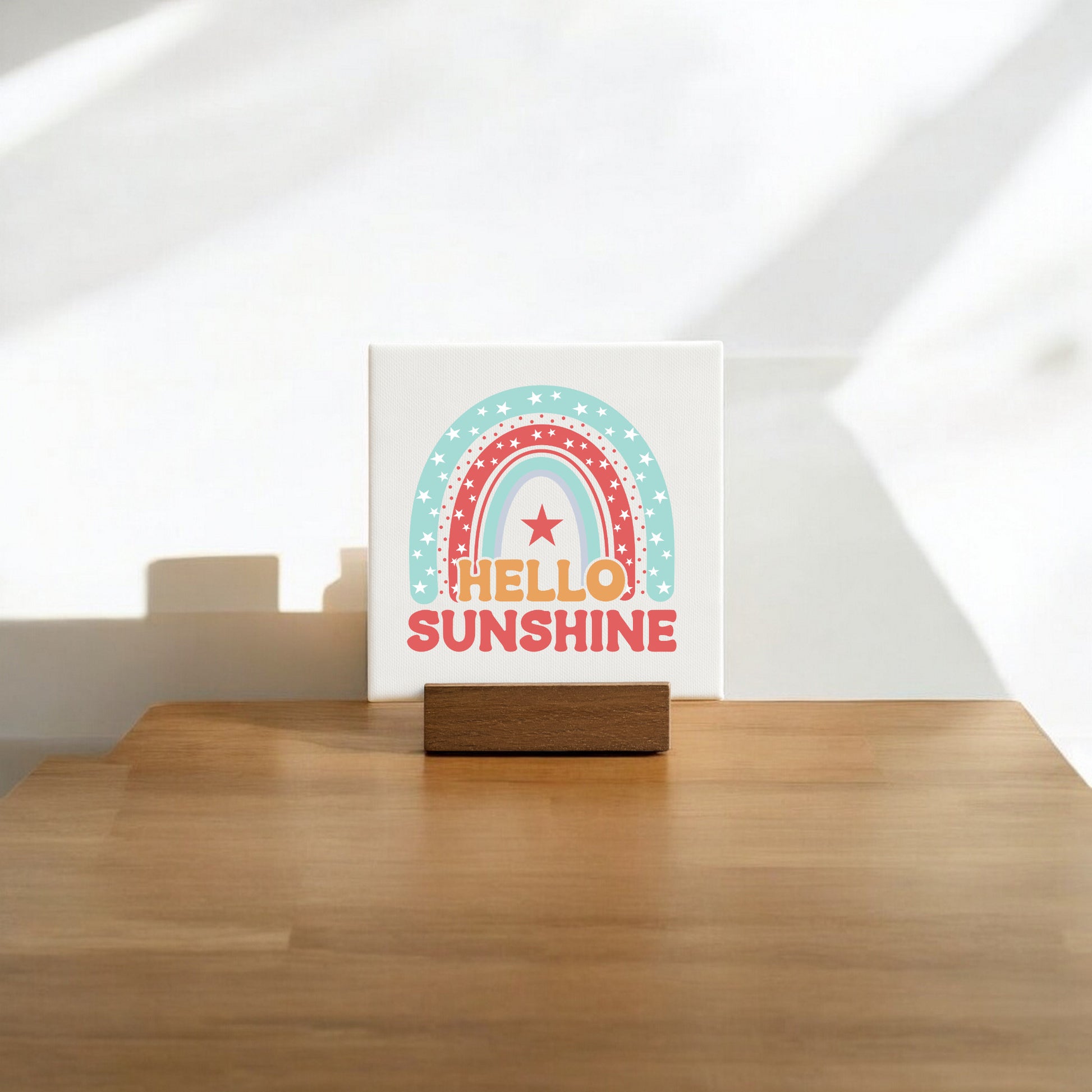 The Mirabilia Boutique Hello Sunshine Mini Canvas Sign with Stand features a pastel rainbow and star design, bold orange "HELLO SUNSHINE" text, and comes displayed on a wooden stand—perfect for brightening up any space.