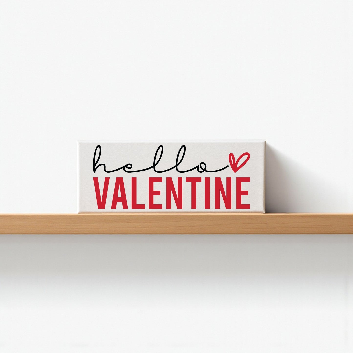 The Mirabilia Boutique Hello Valentine Sign is a modern red and white shelf decor featuring "hello VALENTINE" with a heart, perfect for Valentine’s Day. Its white background adds a romantic touch to your home.