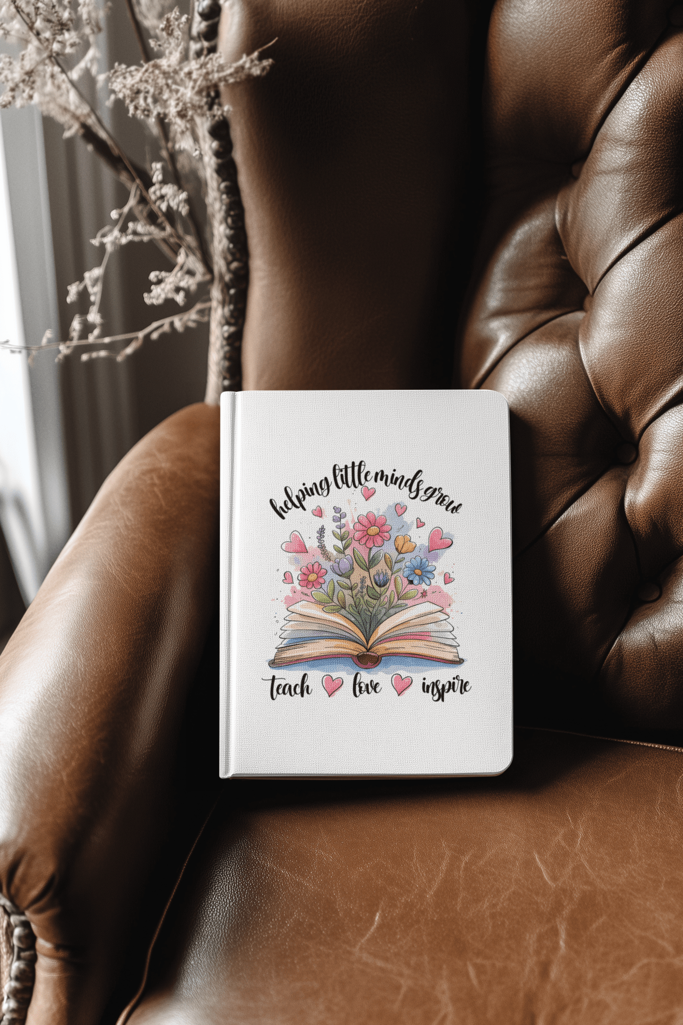 The Mirabilia Boutique Helping Little Minds Grow Hardcover Journal features a white cover with a colorful floral design and open book, plus the text "Helping little minds grow. Teach. Love. Inspire."—a perfect teacher gift notebook.