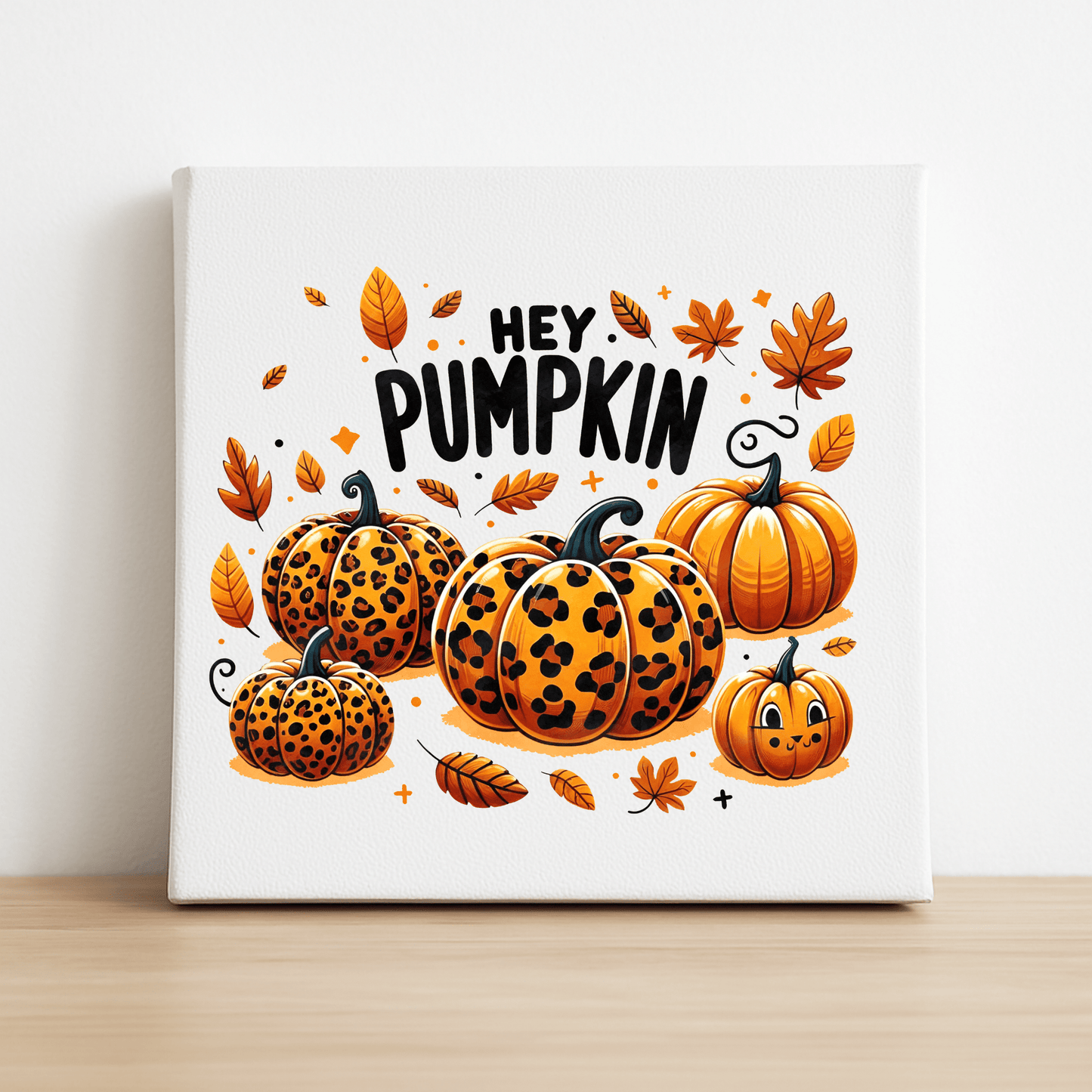 The Mirabilia Boutique Hey Pumpkin Canvas Sign (8x8) features cartoon leopard print pumpkins and autumn leaves, with bold "HEY PUMPKIN" lettering—an ideal fall decor piece for your shelf or wall.