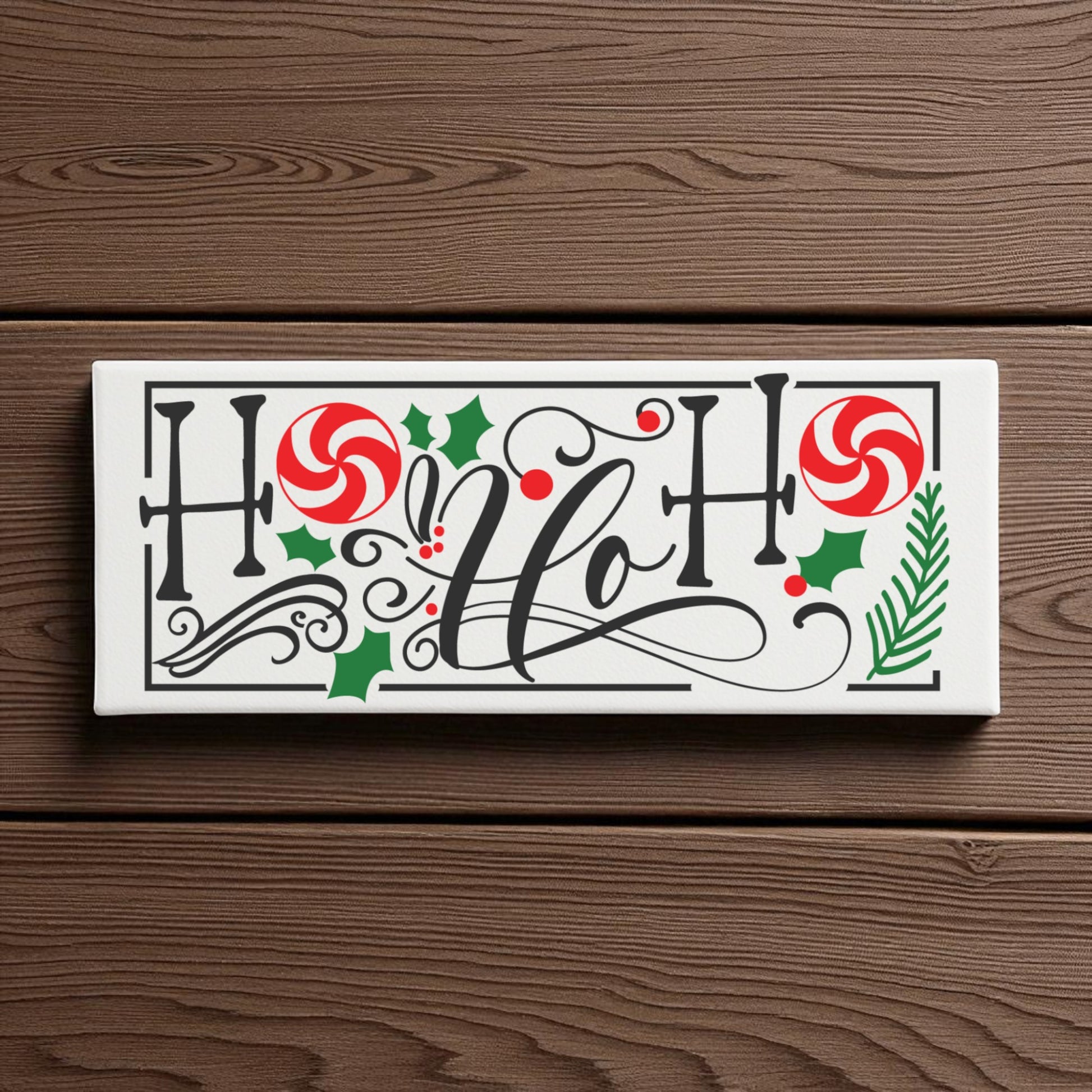 The Mirabilia Boutique Ho Ho Ho Shelf Sitter is a festive Christmas sign with decorative script, red peppermint candies, holly leaves, berries, and a pine sprig, perfect as holiday decor on any wooden surface.