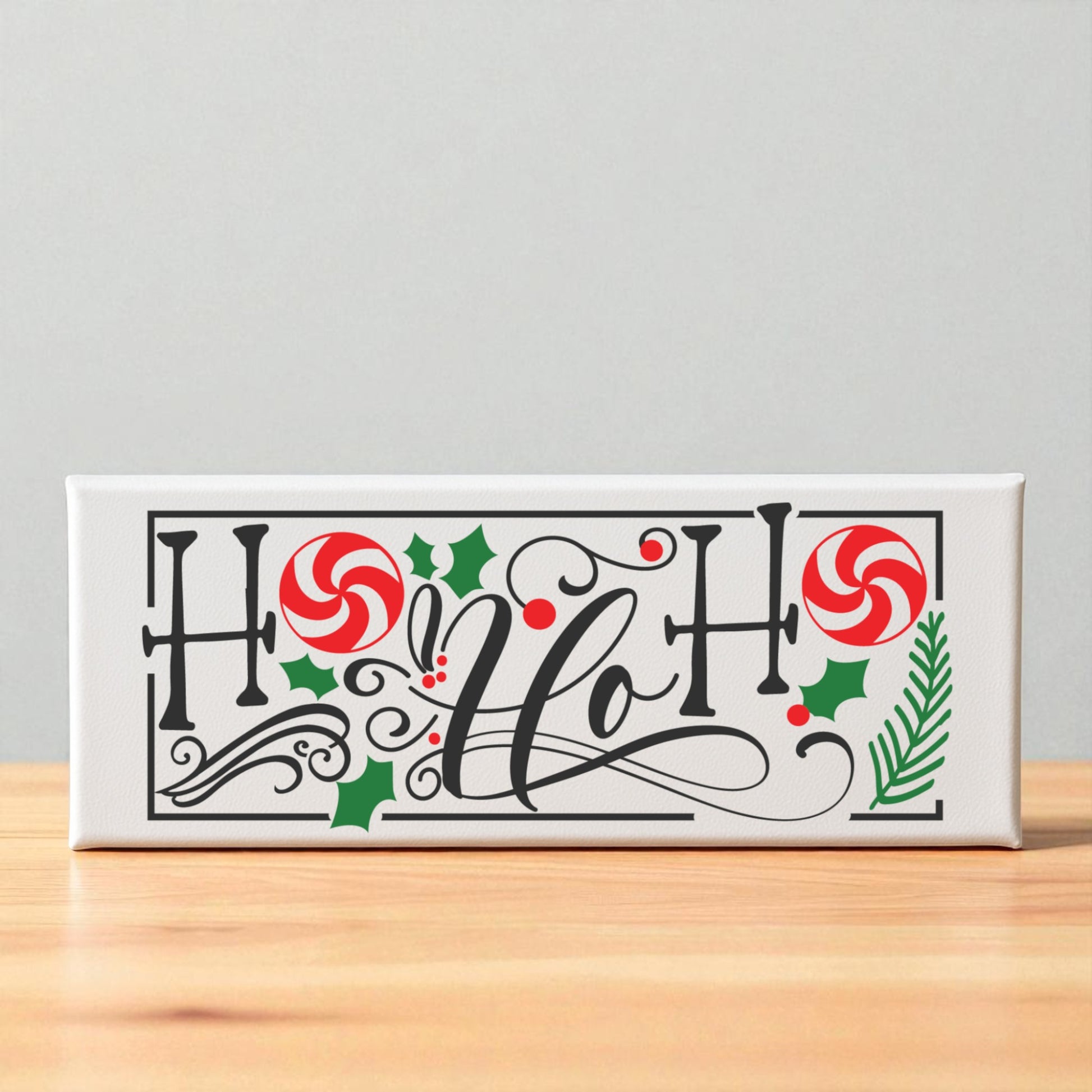 The Mirabilia Boutique Ho Ho Ho Shelf Sitter is a festive Christmas sign featuring “Ho Ho Ho!” in black script with peppermint candies, holly leaves, berries, and pine—perfect holiday decor for your home.
