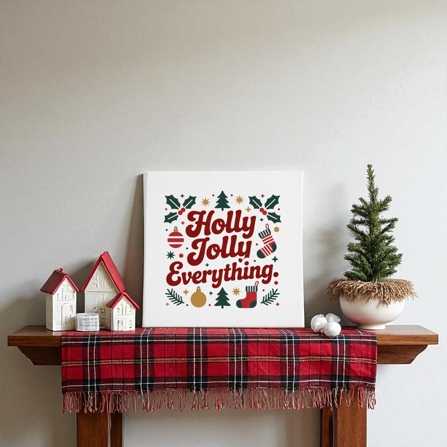 Create a festive mantel with a red plaid cloth, mini white and red house decor, a potted Christmas tree, and Mirabilia Boutique’s “Holly Jolly Everything” 8x8 Christmas Canvas Print for cheerful holiday wall art and decor.