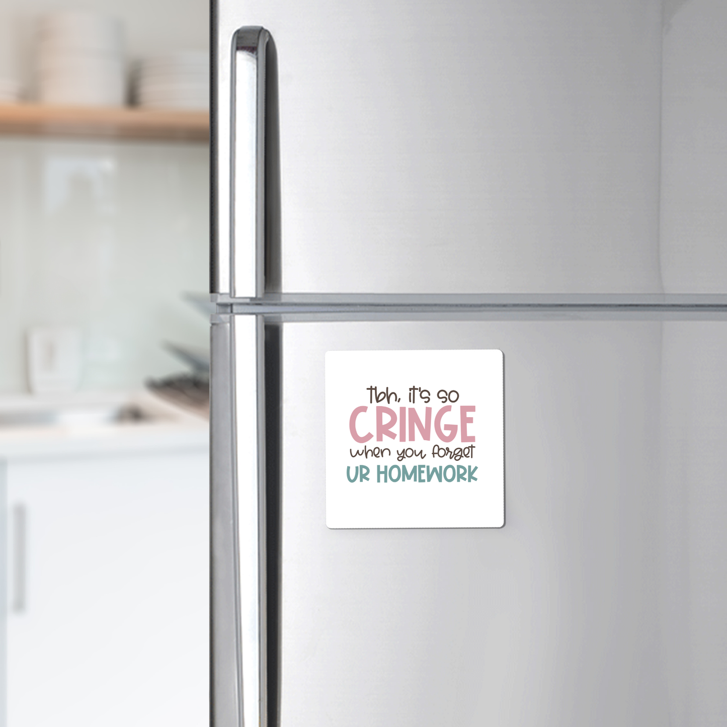 The "It's So Cringe Forget Your Homework Magnet" by Mirabilia Boutique is a square white magnet with playful text, perfect for your fridge. Makes a fun teacher gift or classroom decor—kitchen shelves with dishes in the background.
