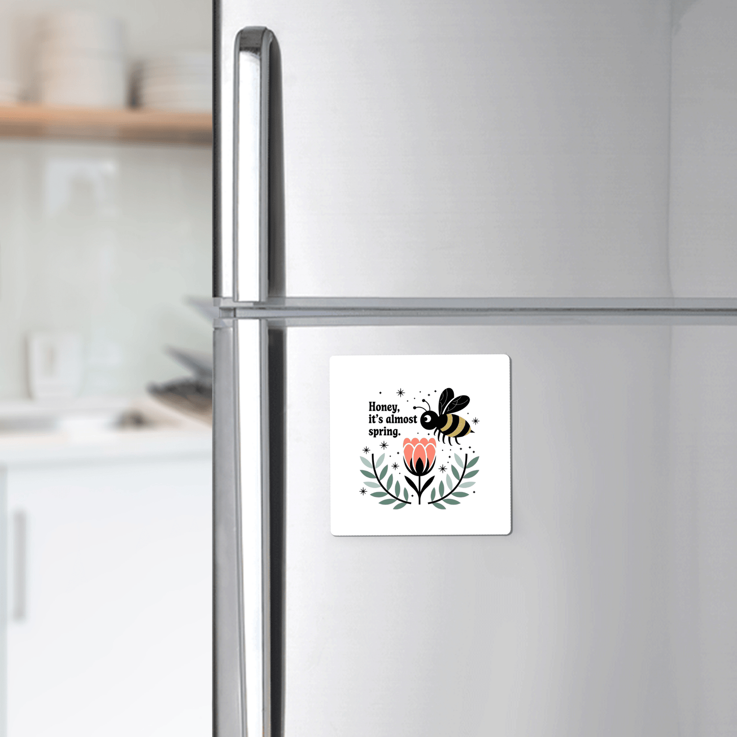 The Honey It’s Almost Spring Magnet by Mirabilia Boutique—a cute bee, pink flower, and green leaves design—brightens your stainless steel fridge, adding the perfect spring touch to any modern kitchen.