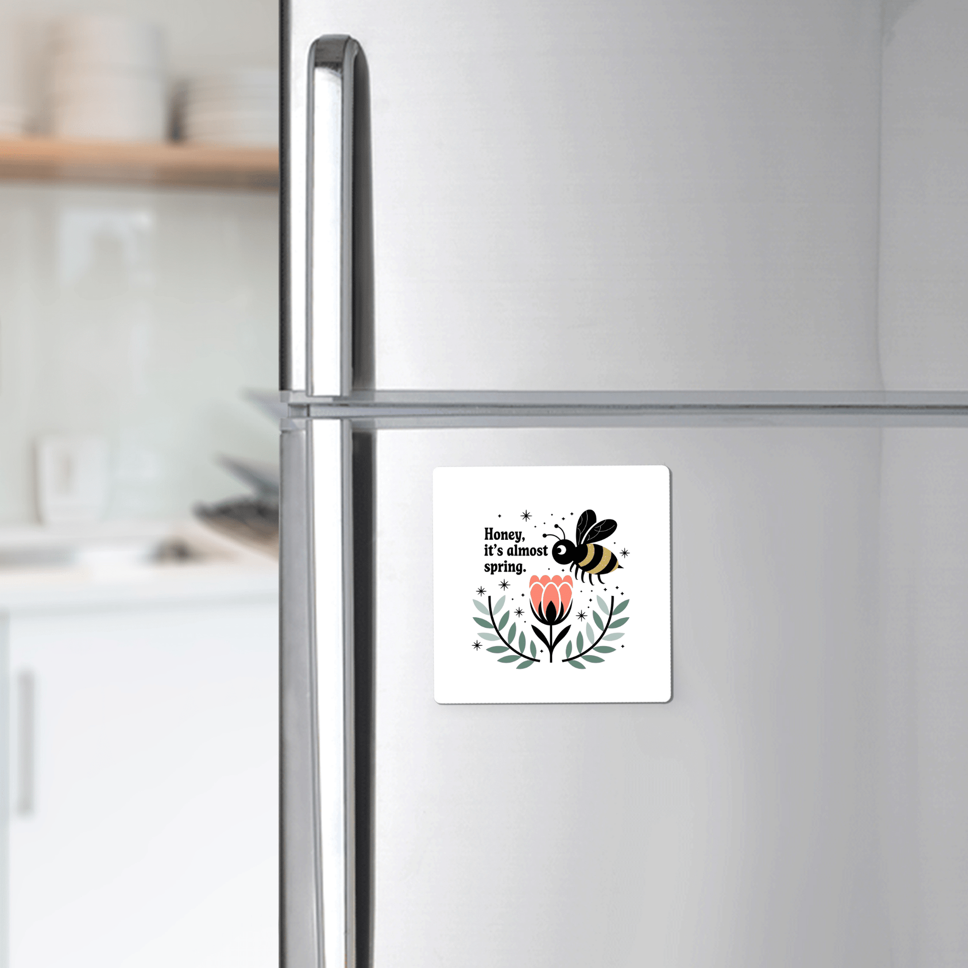 The Honey It’s Almost Spring Magnet by Mirabilia Boutique—a cute bee, pink flower, and green leaves design—brightens your stainless steel fridge, adding the perfect spring touch to any modern kitchen.