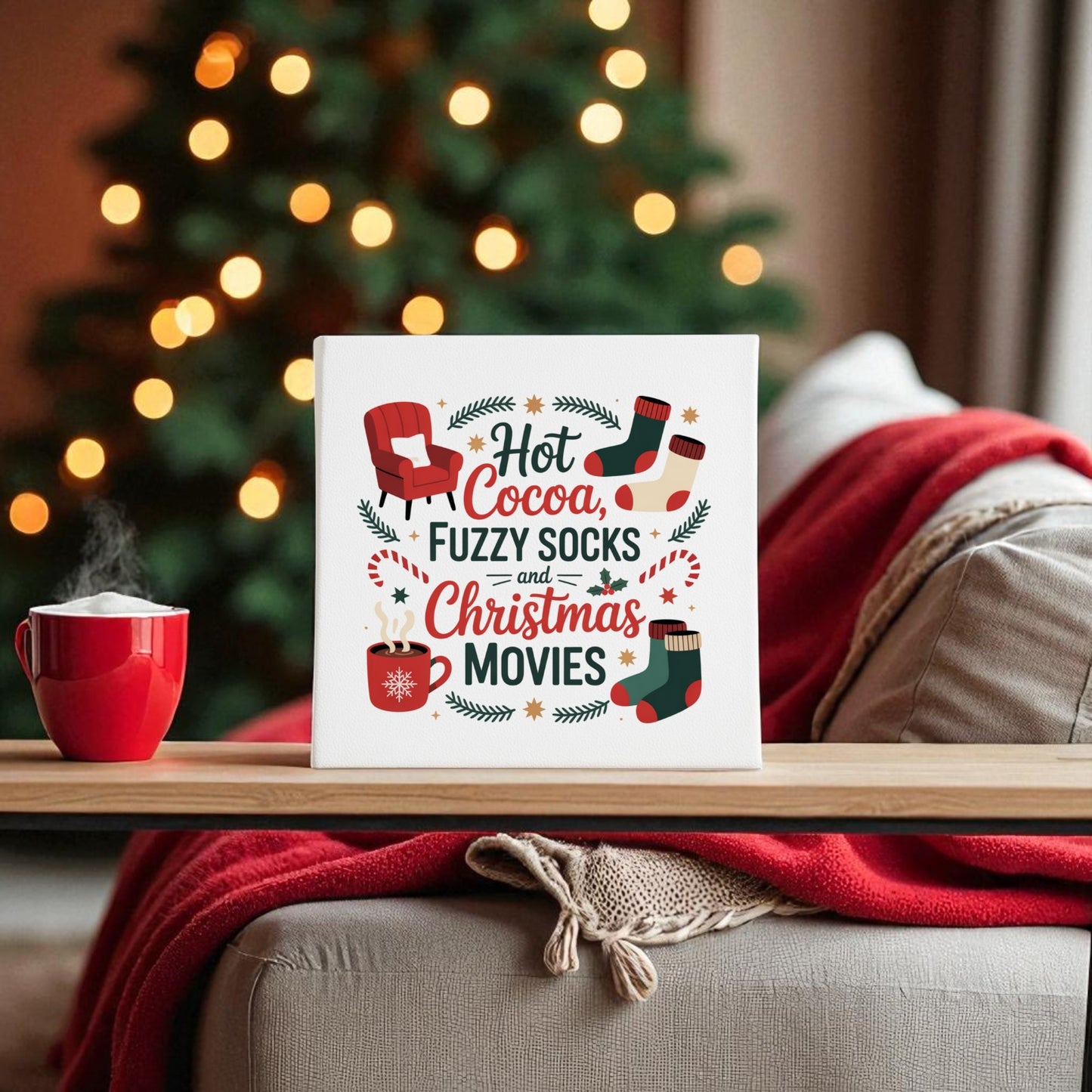 A festive living room with a red mug, cozy blanket, and Mirabilia Boutique’s "Hot Cocoa, Fuzzy Socks, Christmas Movies" 8x8 holiday canvas sign—plus a glowing tree—creates the perfect cozy Christmas gift setting.