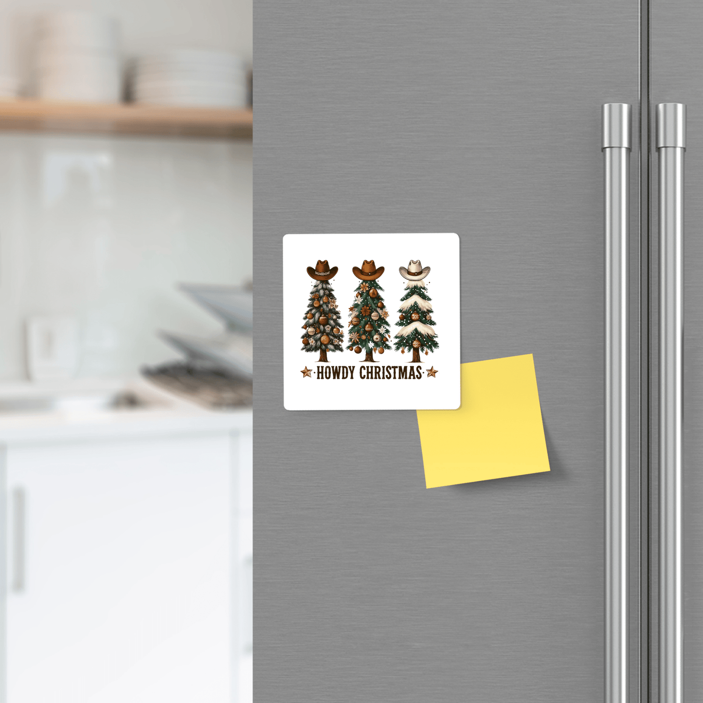 The Howdy Christmas Magnet by Mirabilia Boutique features three cowboy-hat Christmas trees and “Howdy Christmas” text on a fridge. A yellow sticky note is attached, with a kitchen in the background. Perfect Western holiday decor!.